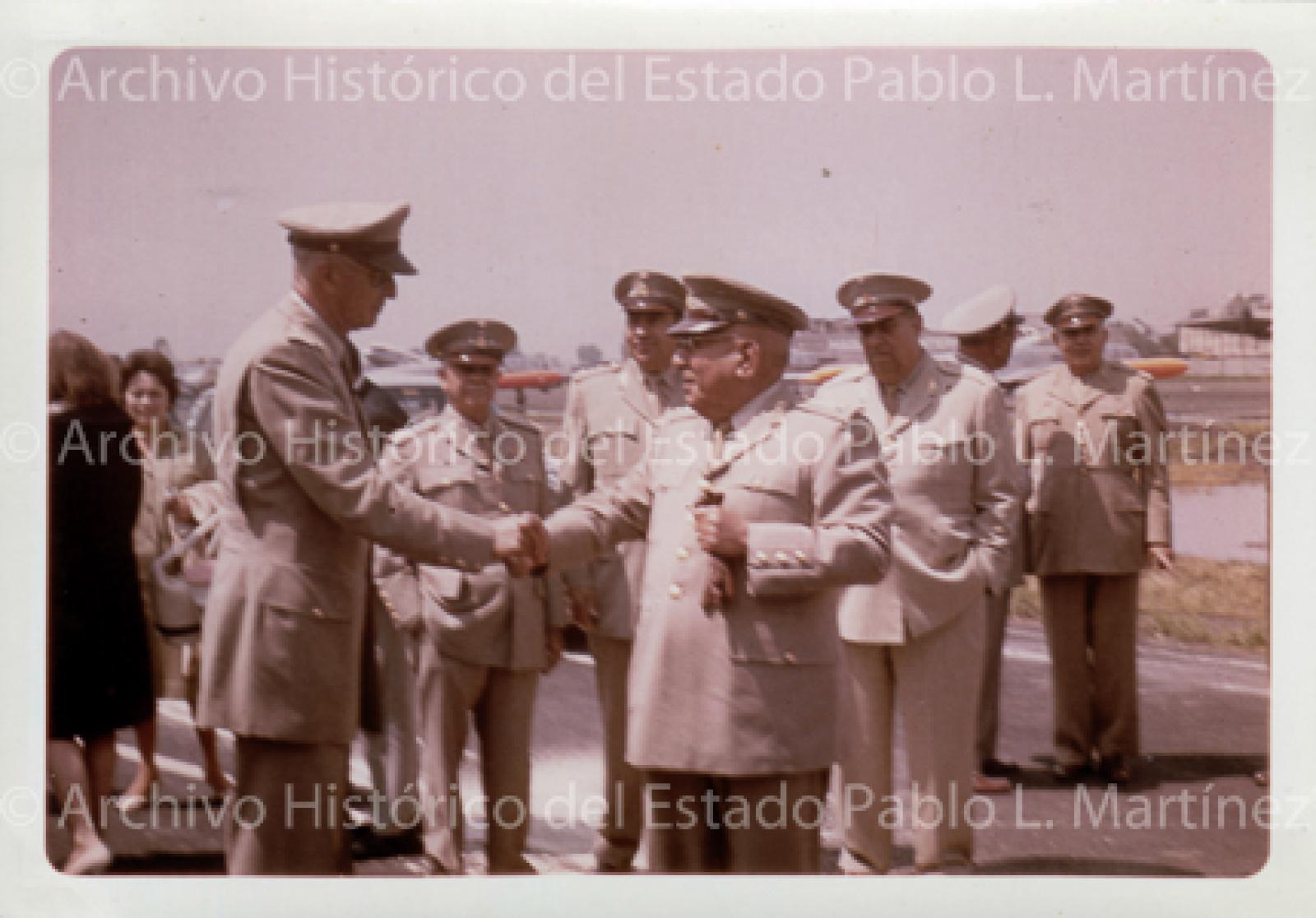Agustín Olachea Avilés, saluda a militar en campo aéreo.
