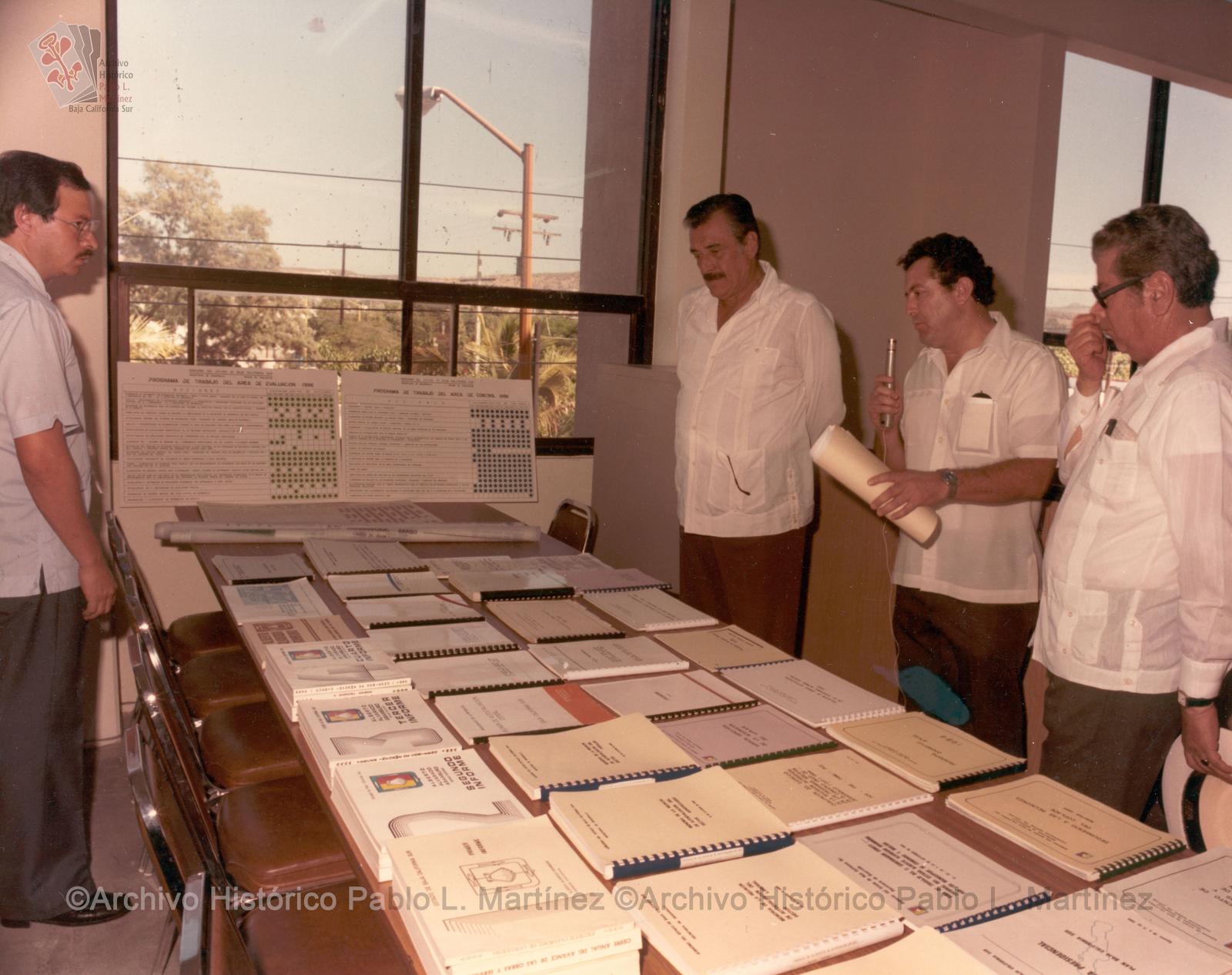 Alberto Andrés Alvarado Arámburo y funcionarios públicos observando libros e informes de gobierno.
