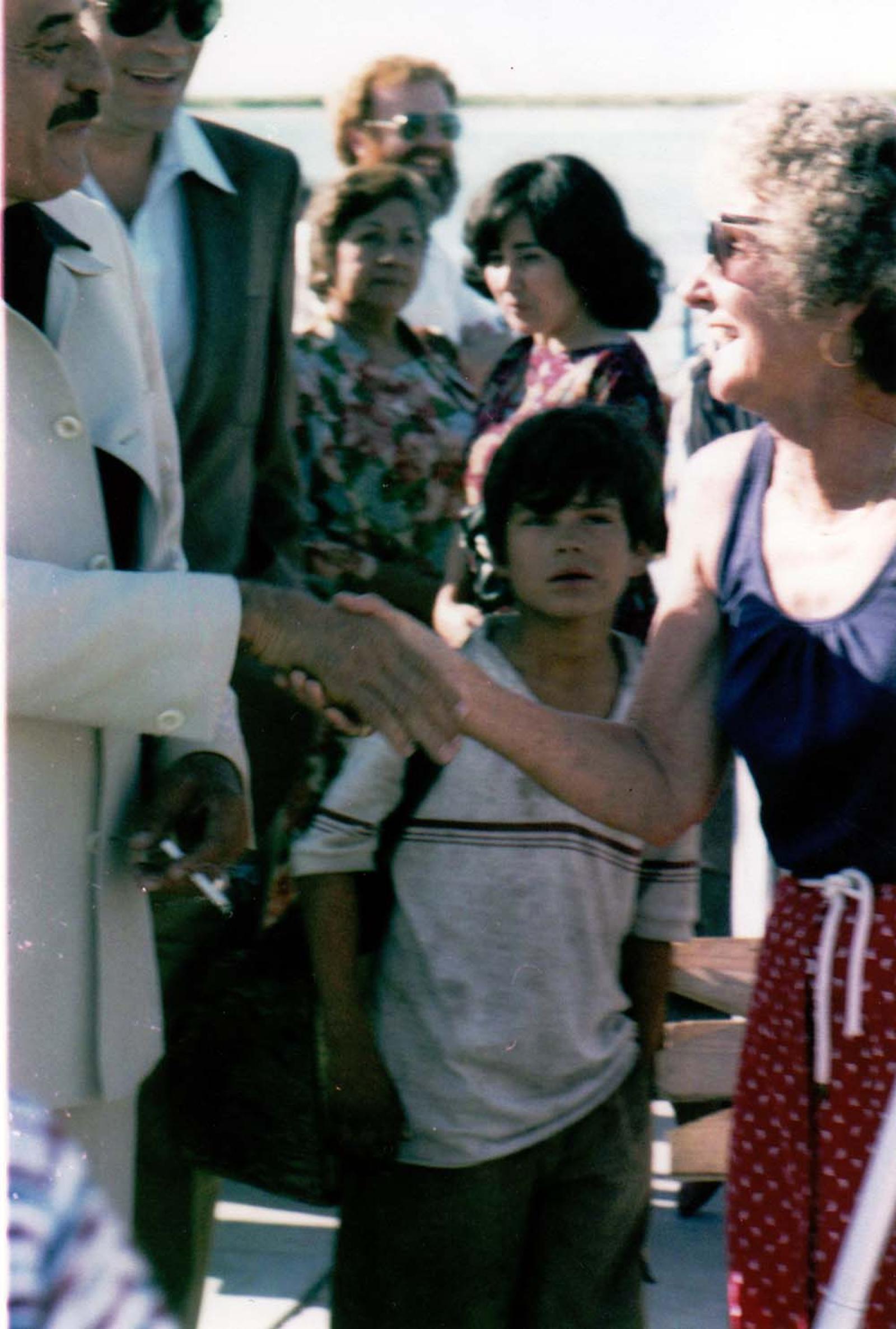 Alberto Andrés Alvarado saluda a mujer, frente a público.