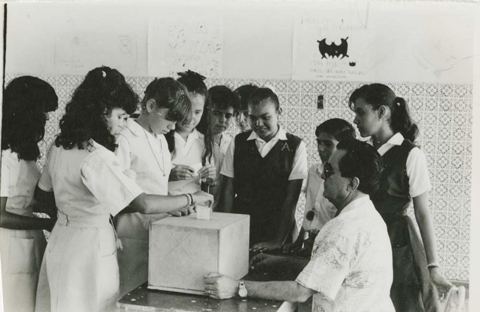 Alumnas emiten voto en urna.