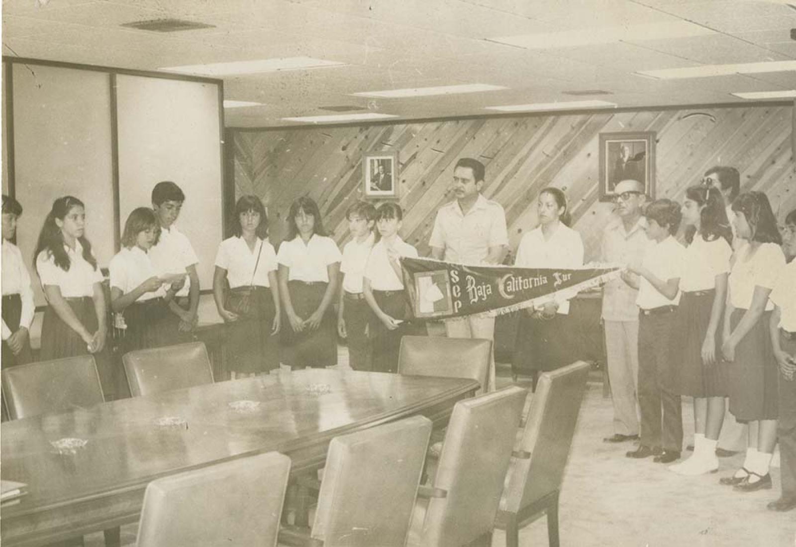 Alumnos, hombres y mujer en sala de juntas.