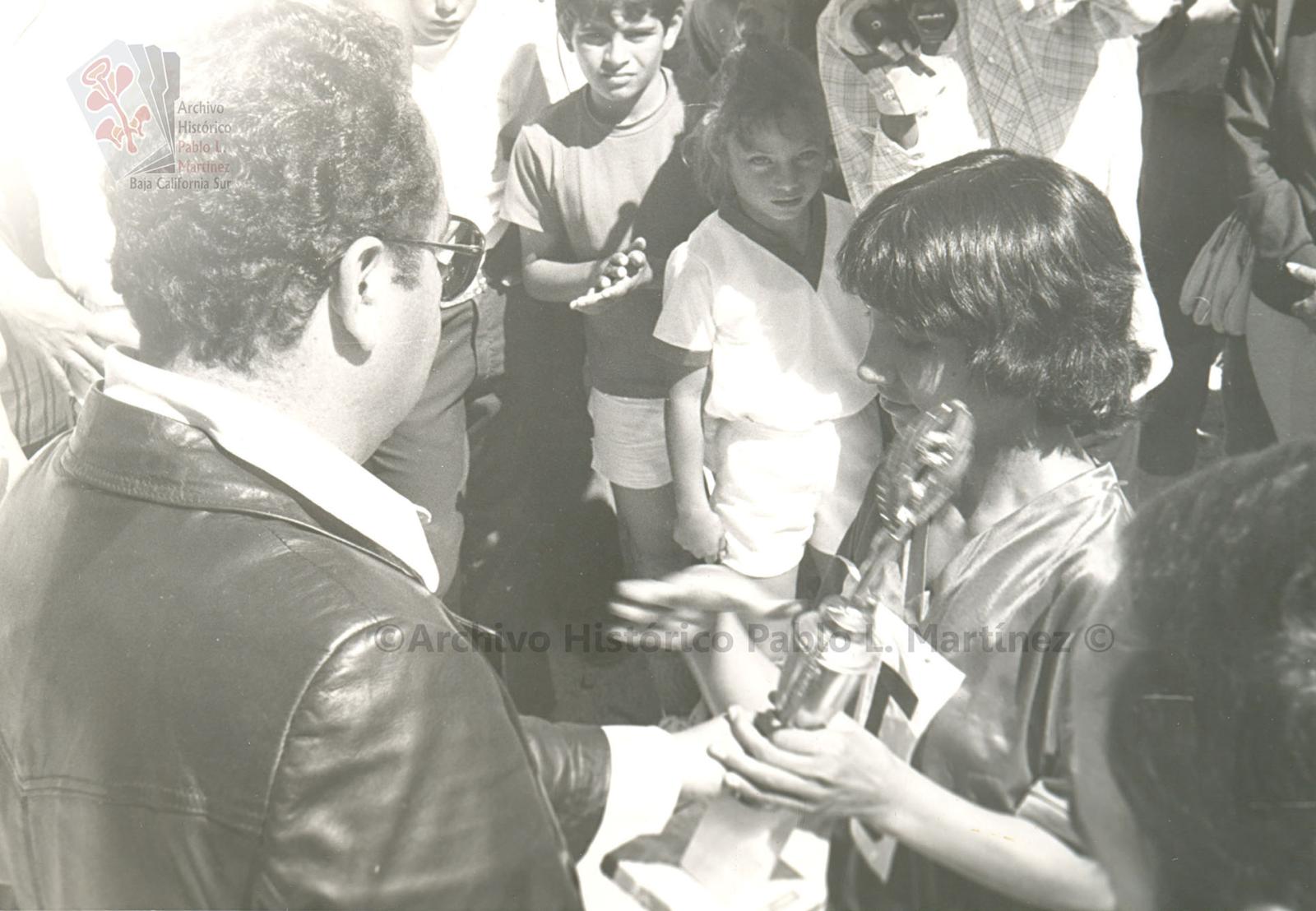 Ángel César Mendoza Arámburo entrega un trofeo a una niña.