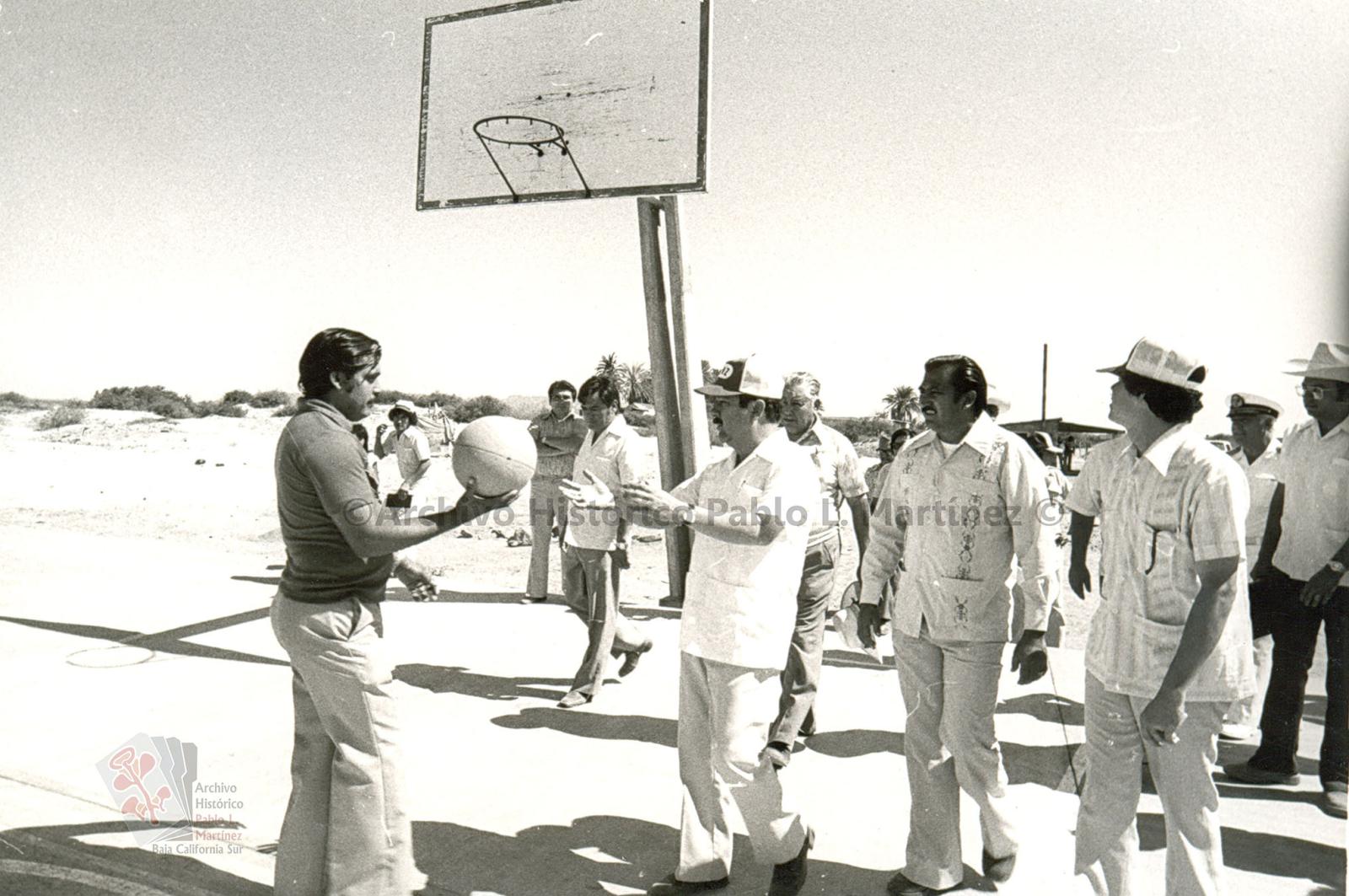 Ángel César Mendoza Arámburo y acompañantes en cancha de basquetbol.