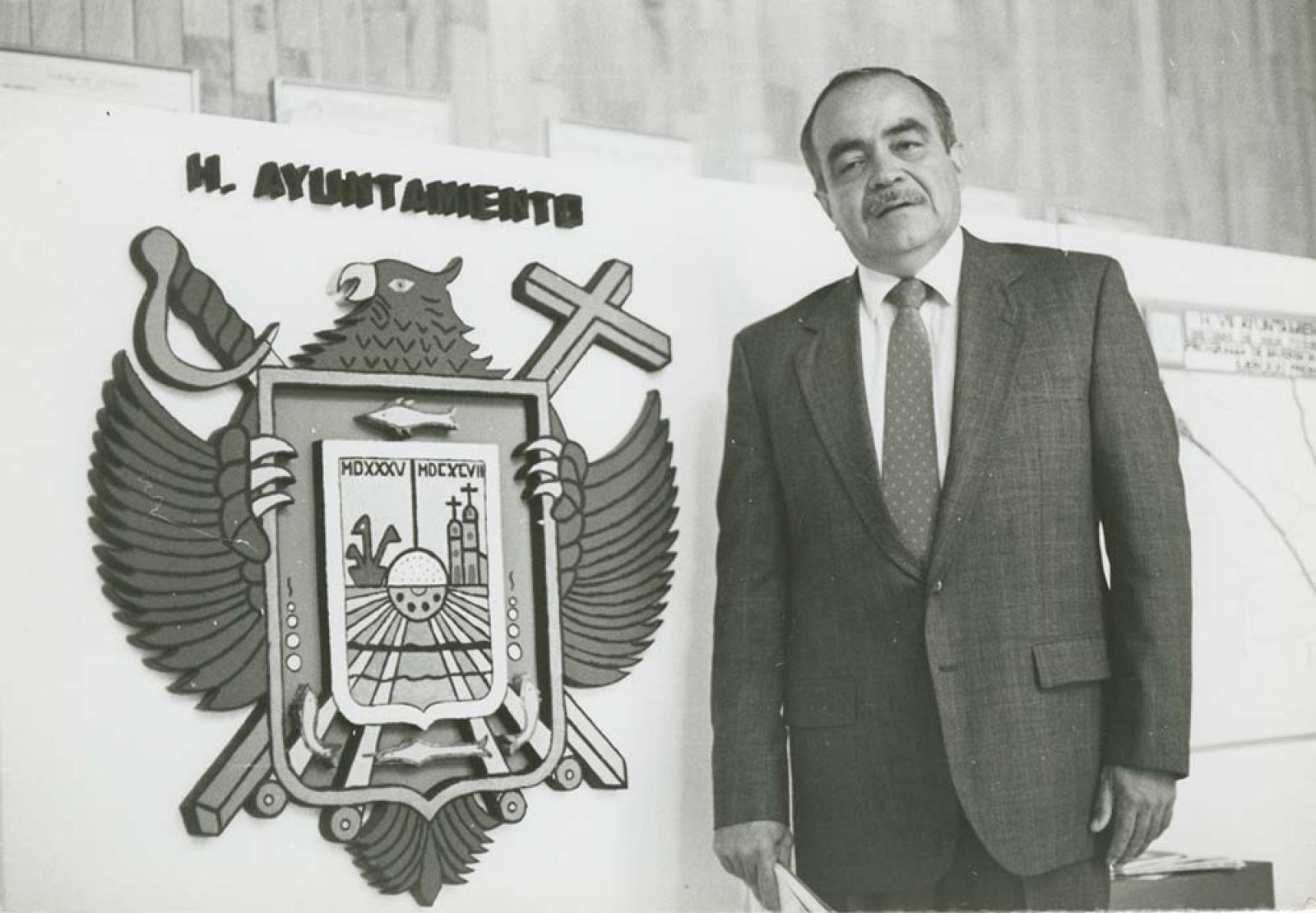 Antonio Wilson González, junto a escudo del Ayuntamiento de La Paz, Baja California Sur.