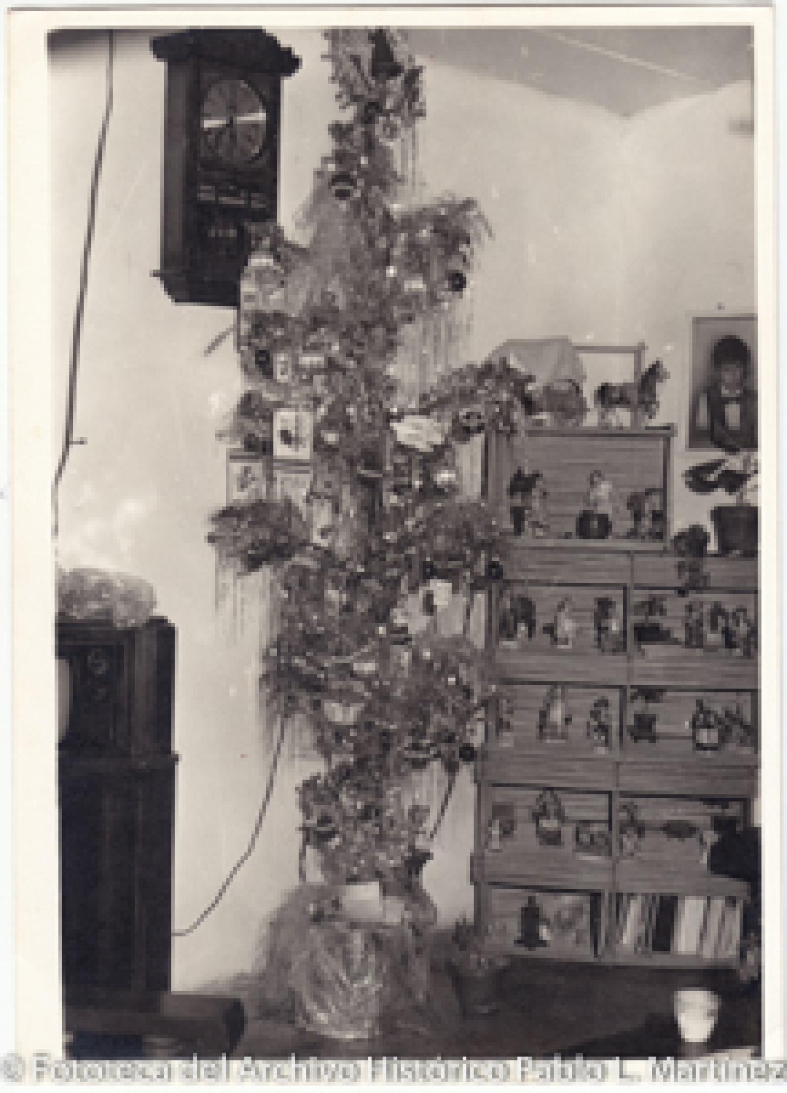 Árbol de navidad frente a reloj  y juguetero.