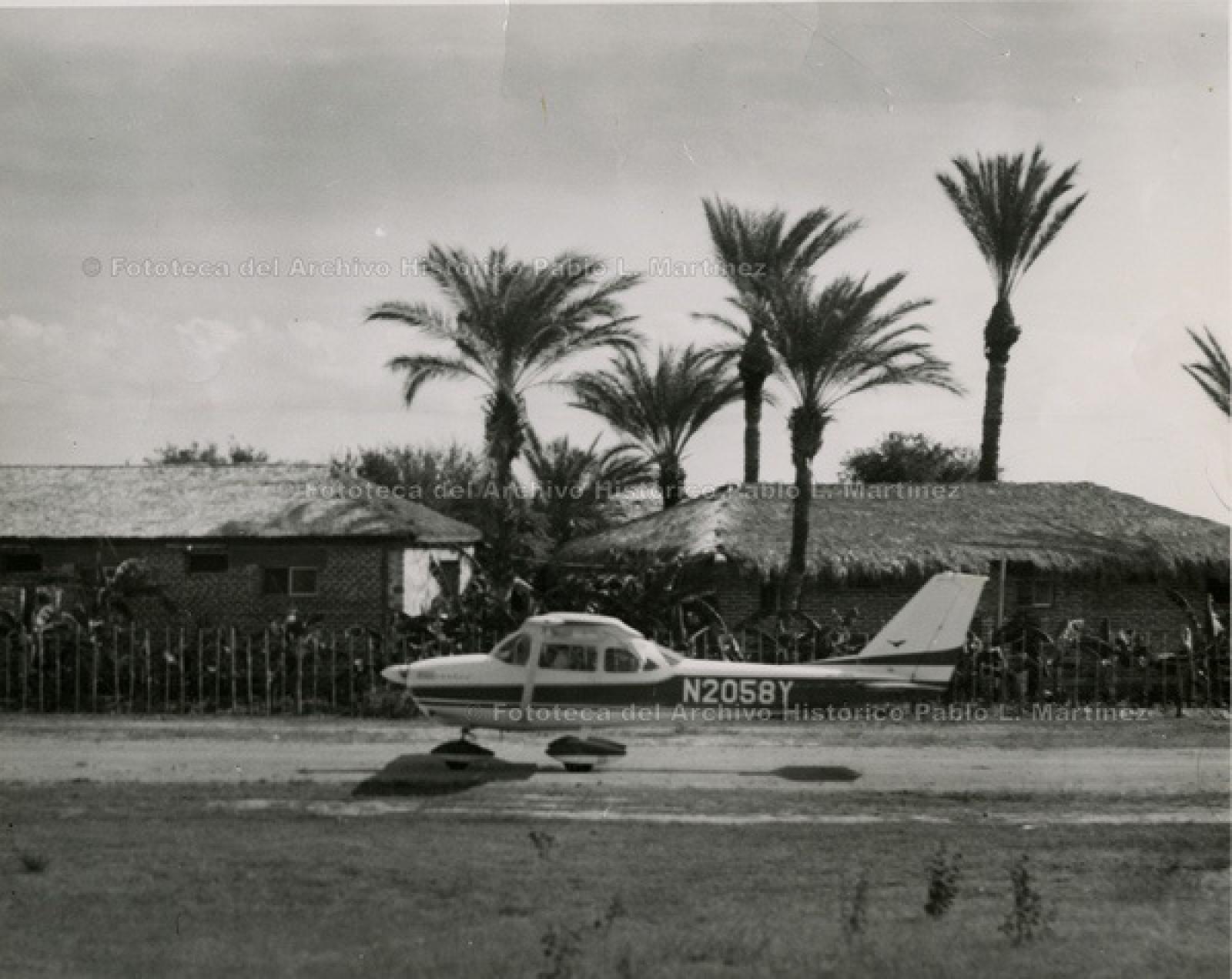 Avioneta estacionada en camino frente a casas, en zona rural.