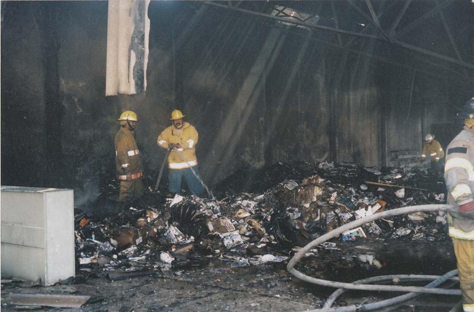 Bomberos apagan incendio en interior de construcción.