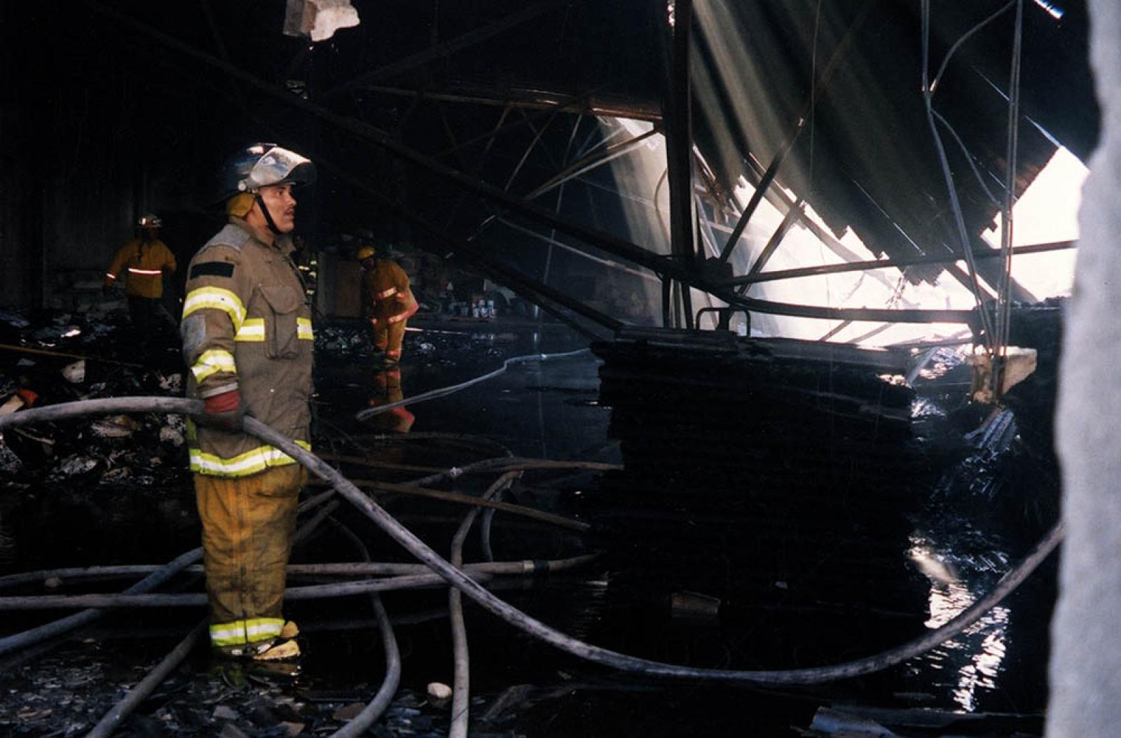 Bomberos en bodega en ruinas por incendio.