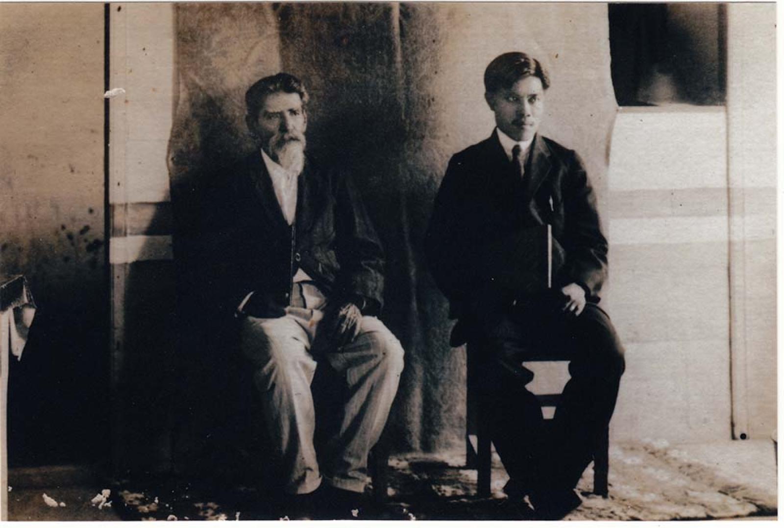 Dos Hombres sentados en estudio fotográfico.