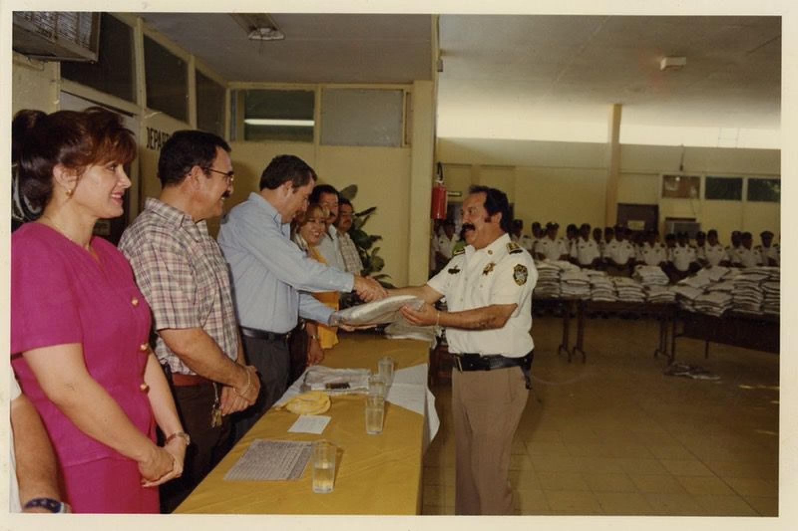 El gobernador Leonel Cota Montaño entrega uniforme a policía durante ceremonia.