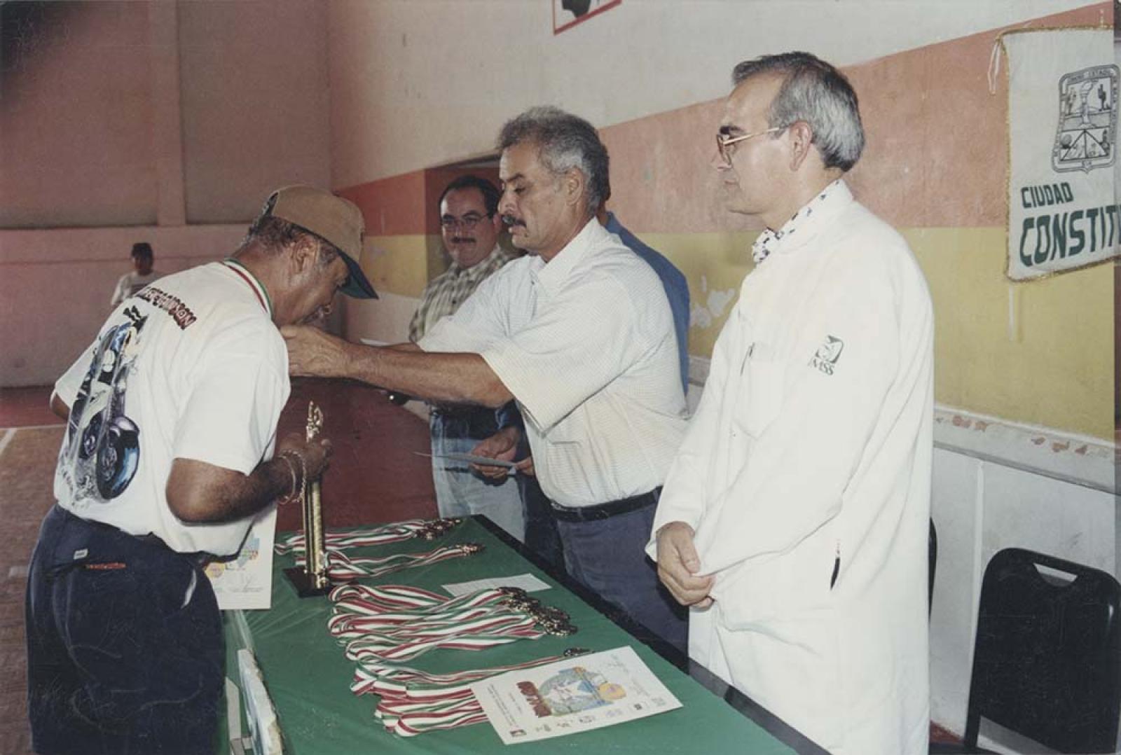 “El Secretario General del Ayuntamiento, Fernando Ramírez Mercado, entrega medalla a participante en la Olimpiada Estatal”.