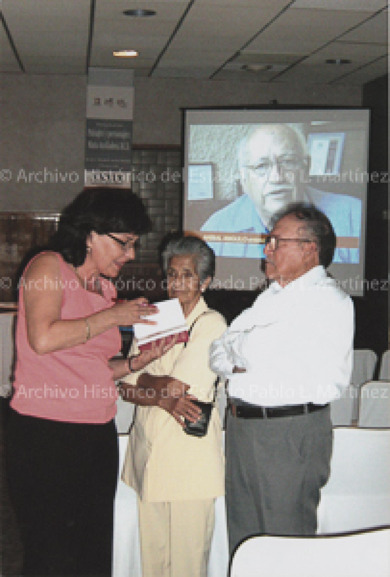 Elizabeth Acosta escribe dedicatoria en libro, a público asistente.
