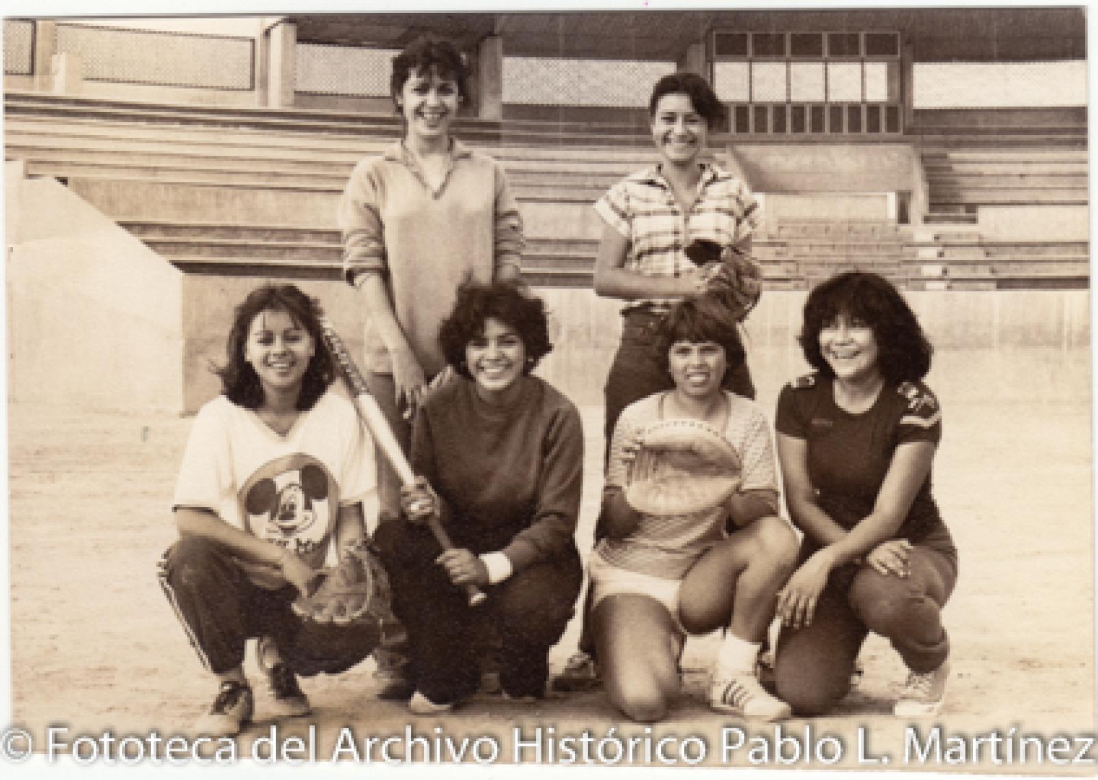 Equipo femenino de béisbol, en campo deportivo.