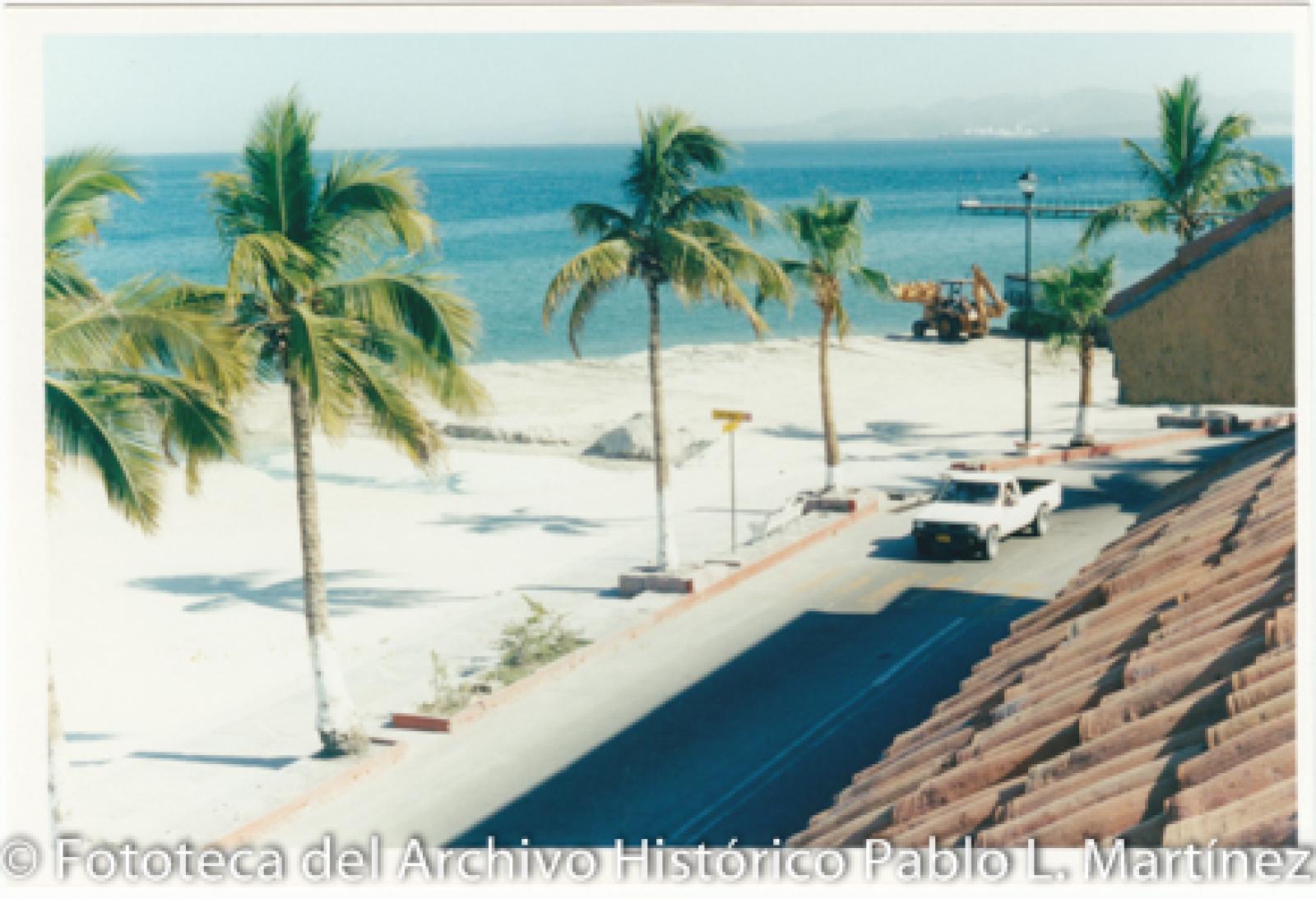 Excavadora que esparce arena en la playa, malecón de La Paz.