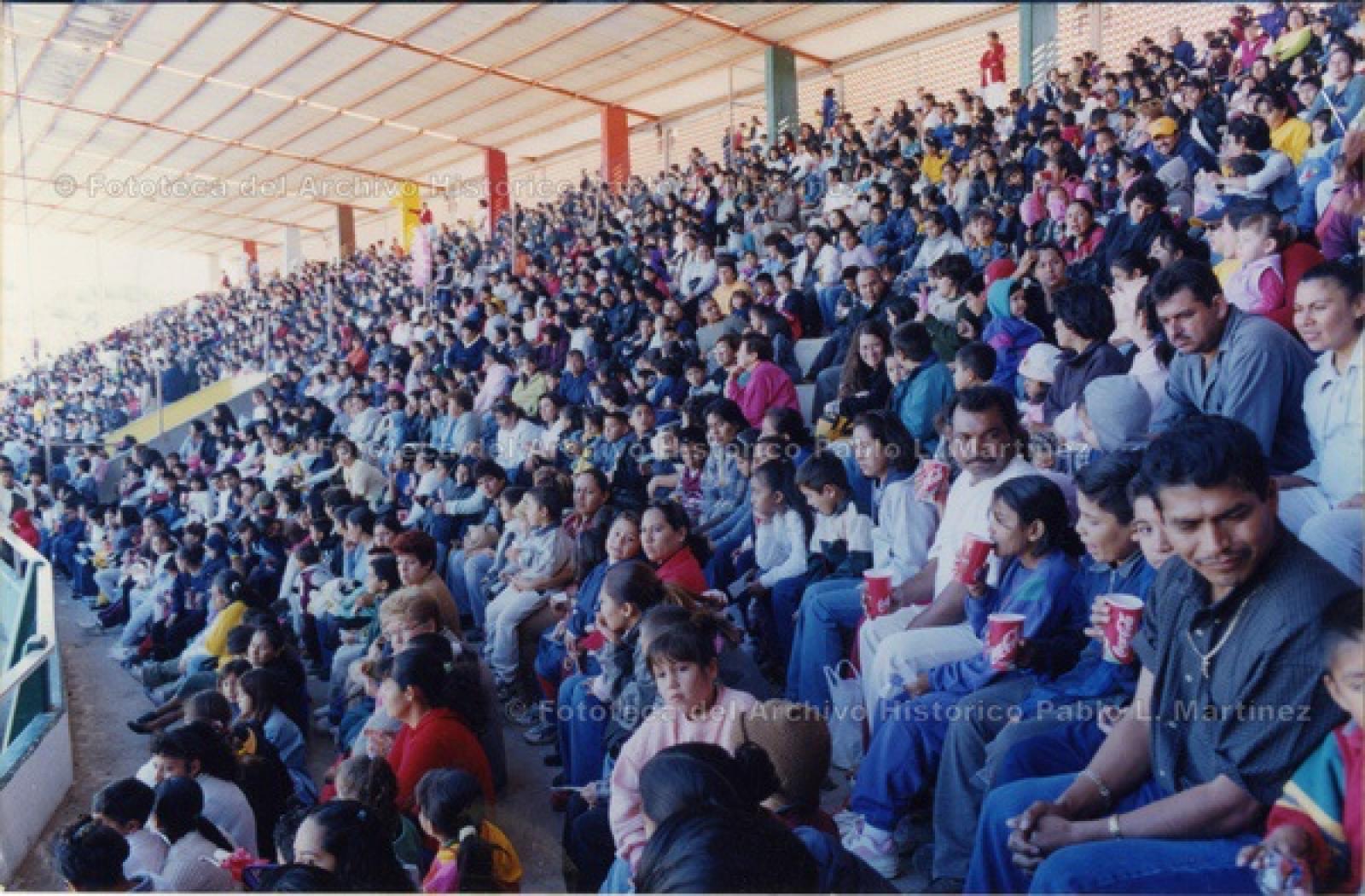 Expectadores sentados en gradas.