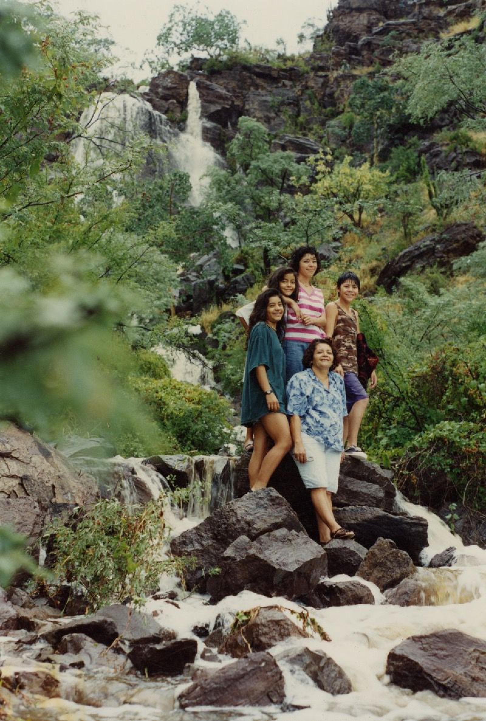 Familia sobre rocas entre arroyo.