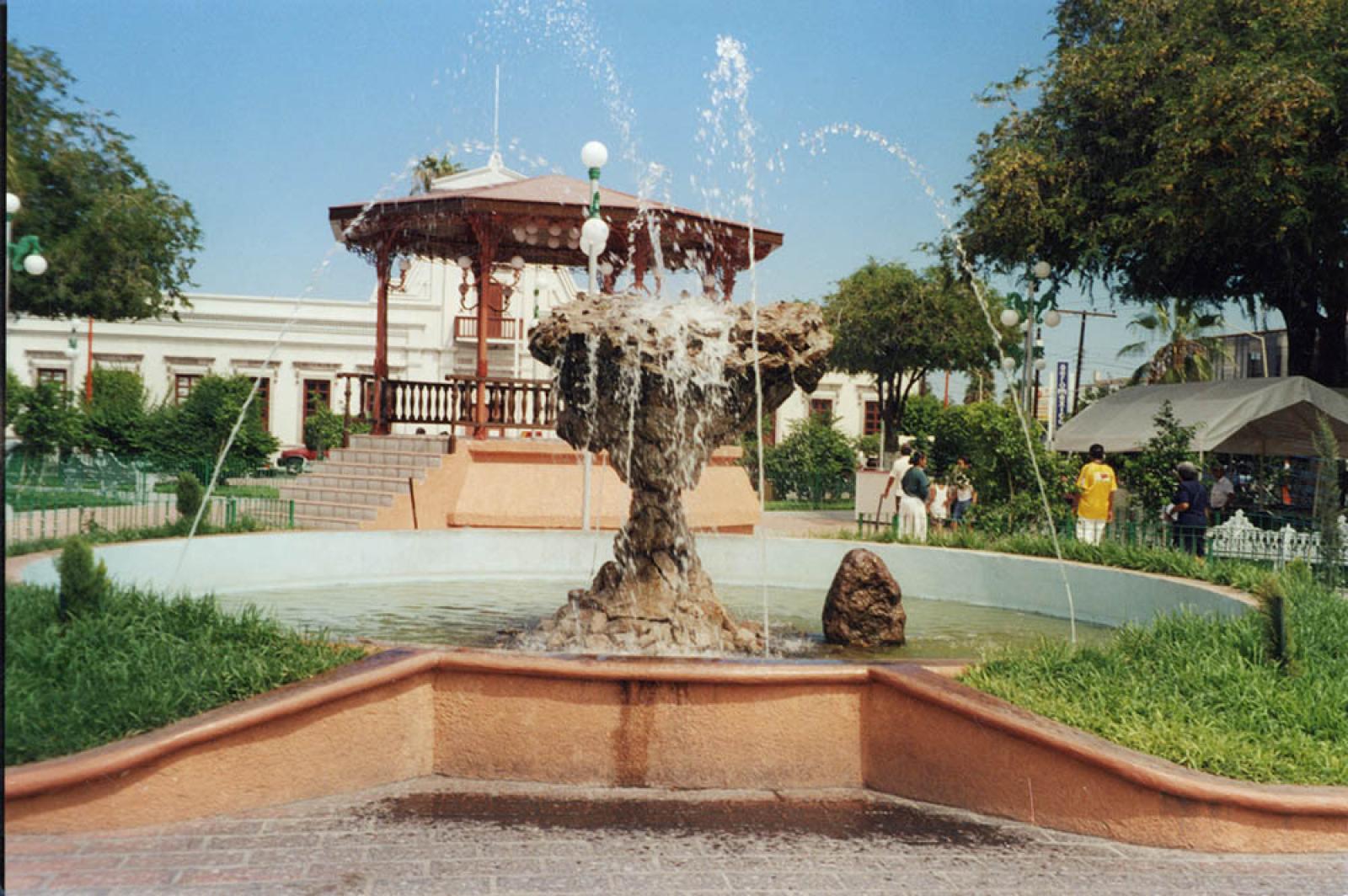 Fuente y kiosco del jardín Velasco, al fondo, la antigua Casa de Gobierno.