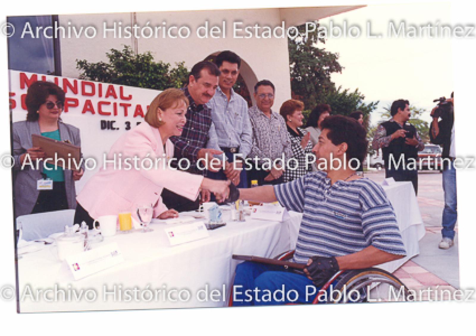 Guillermo Mercado Romero y Concepción Casas de Mercado entregan reconocimiento apersona en silla de ruedas.