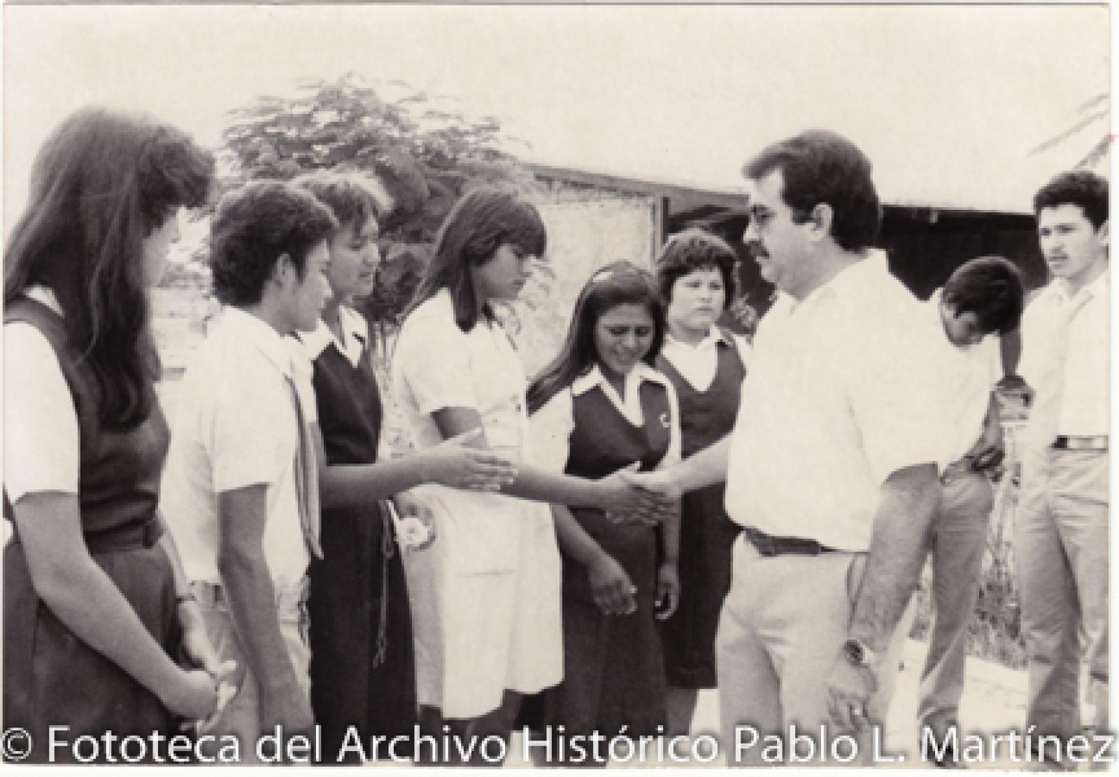 Hombre acompañado de estudiantes de secundaria.