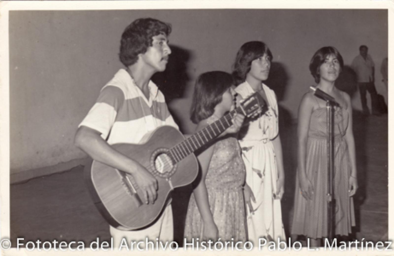 Hombre con guitarra y mujeres que cantan