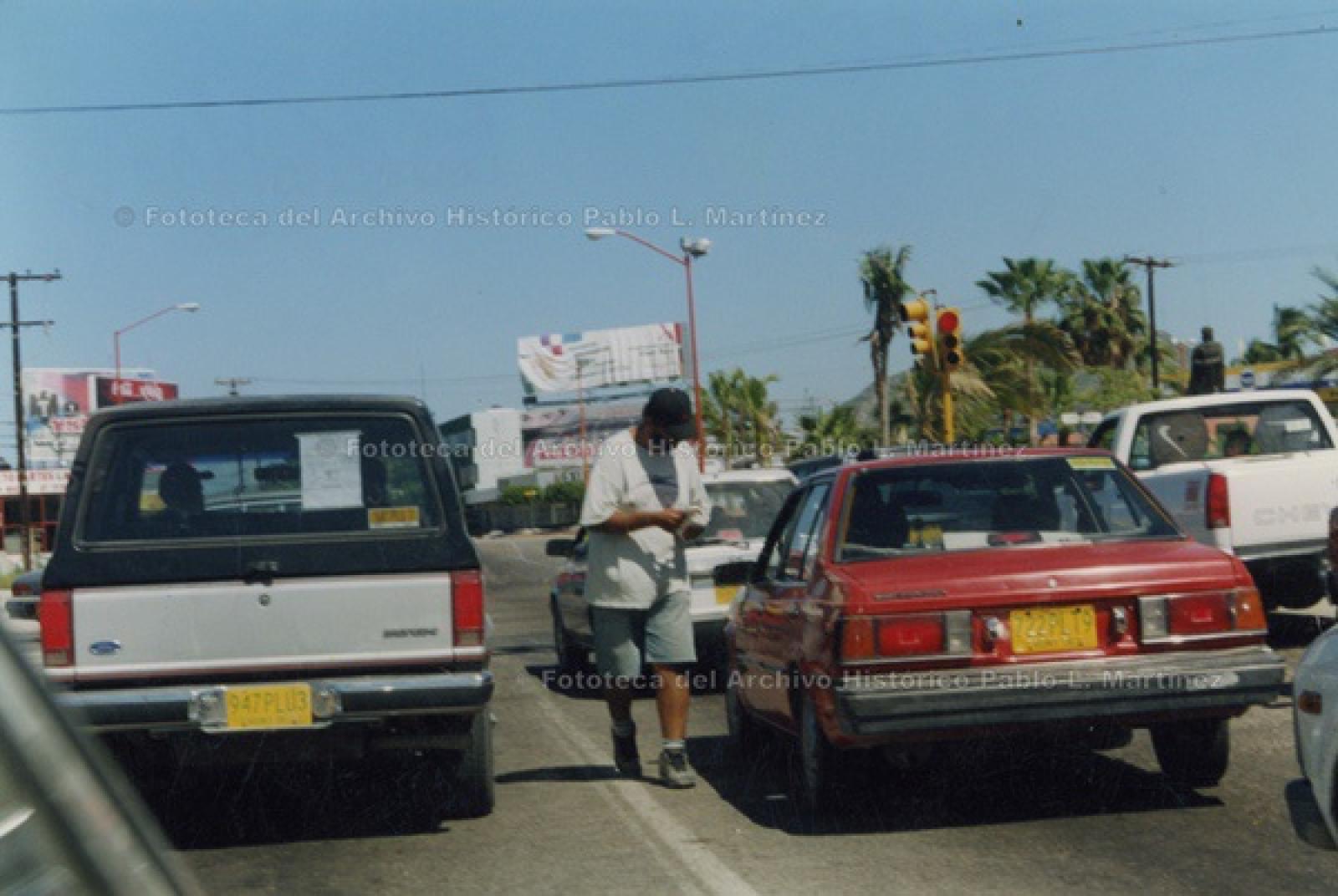 Hombre entre tráfico vehicular, a un costado del parque Morelos, La Paz.
