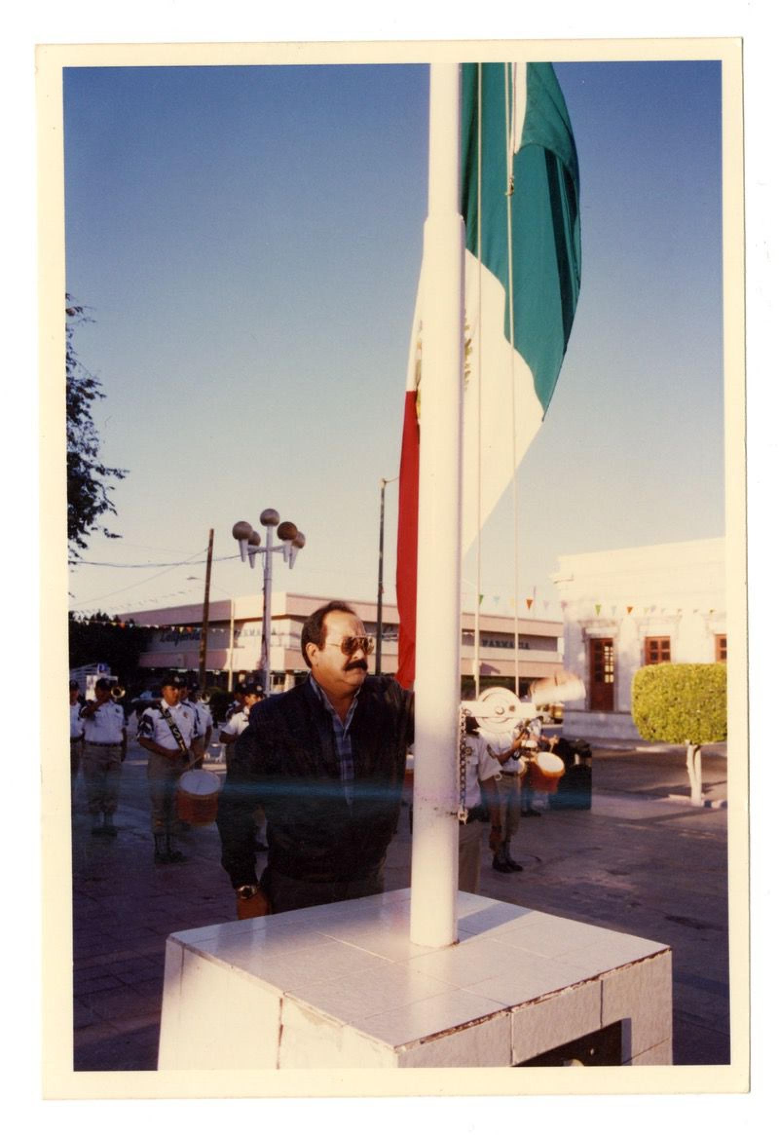 Hombre izando la bandera nacional en el jardín Velasco.