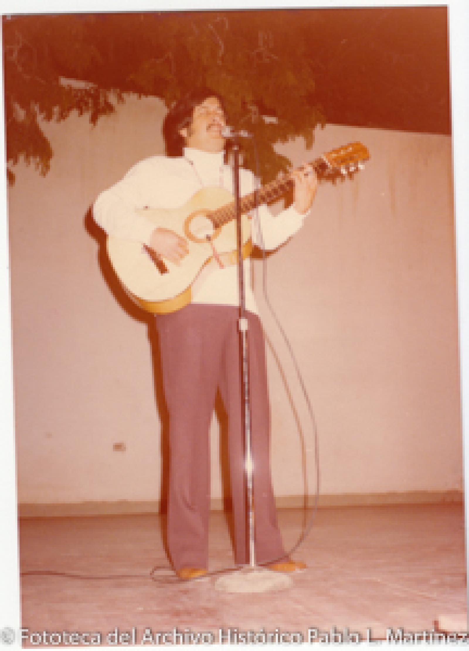Hombre que canta y toca la guitarra.
