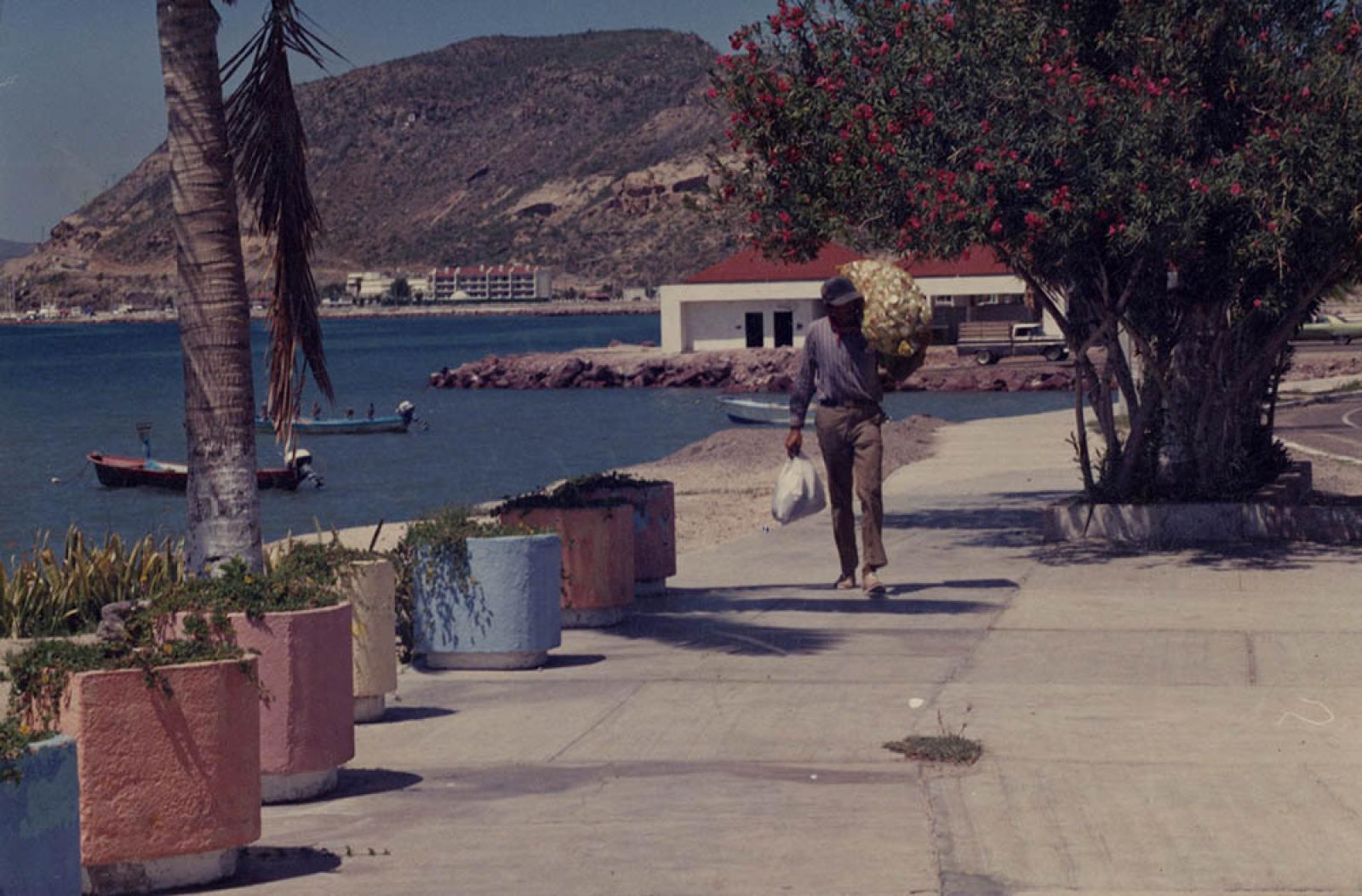 Hombre que carga costal con botes de aluminio, malecón de La Paz, Baja California Sur.