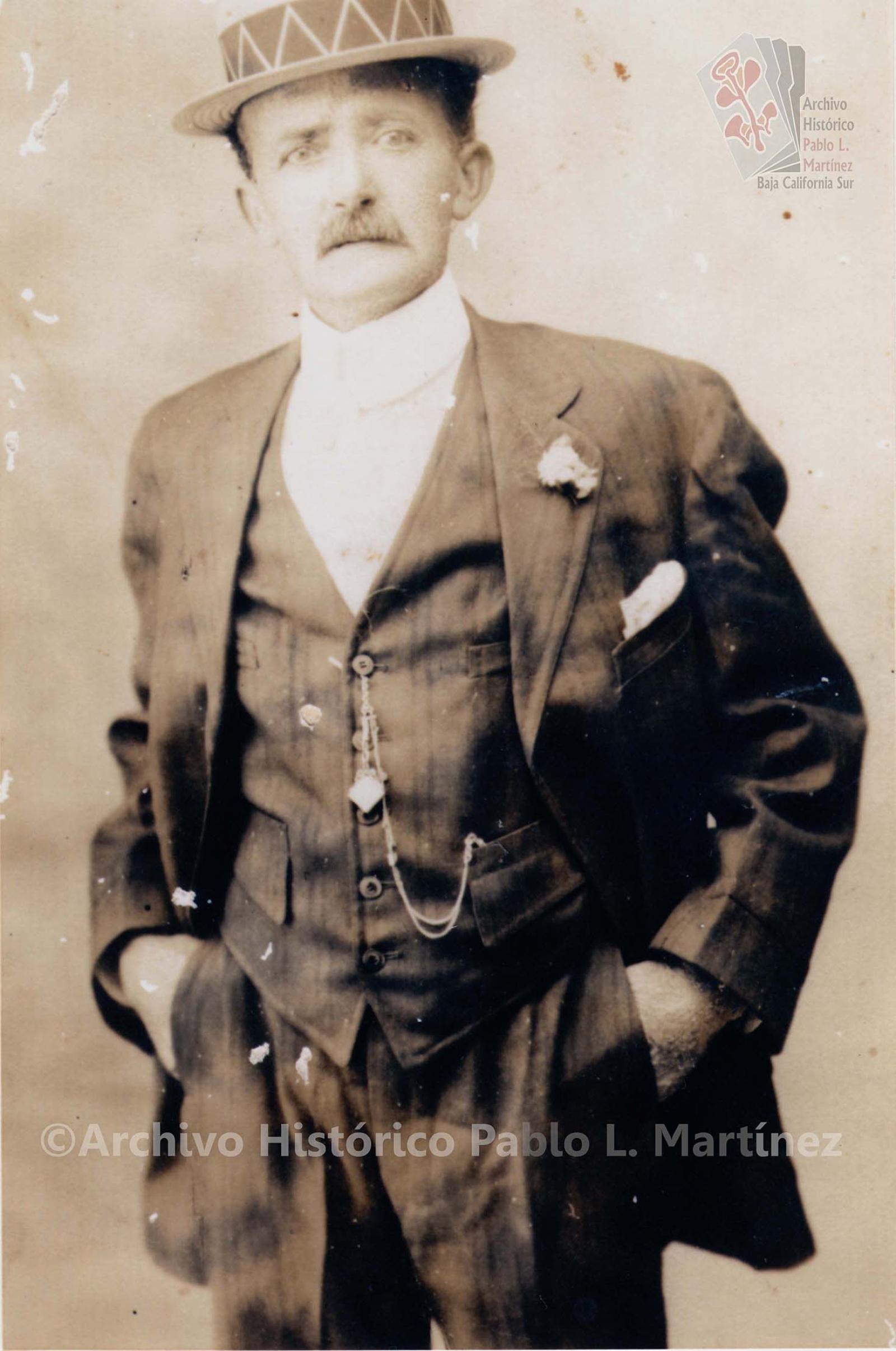 Hombre que porta su traje elegante y lo adorna con su sombrero.