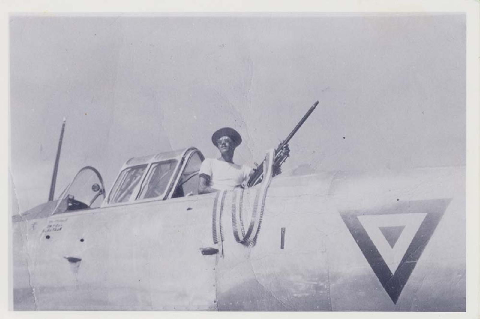Hombre que sostiene metralleta, en avioneta.