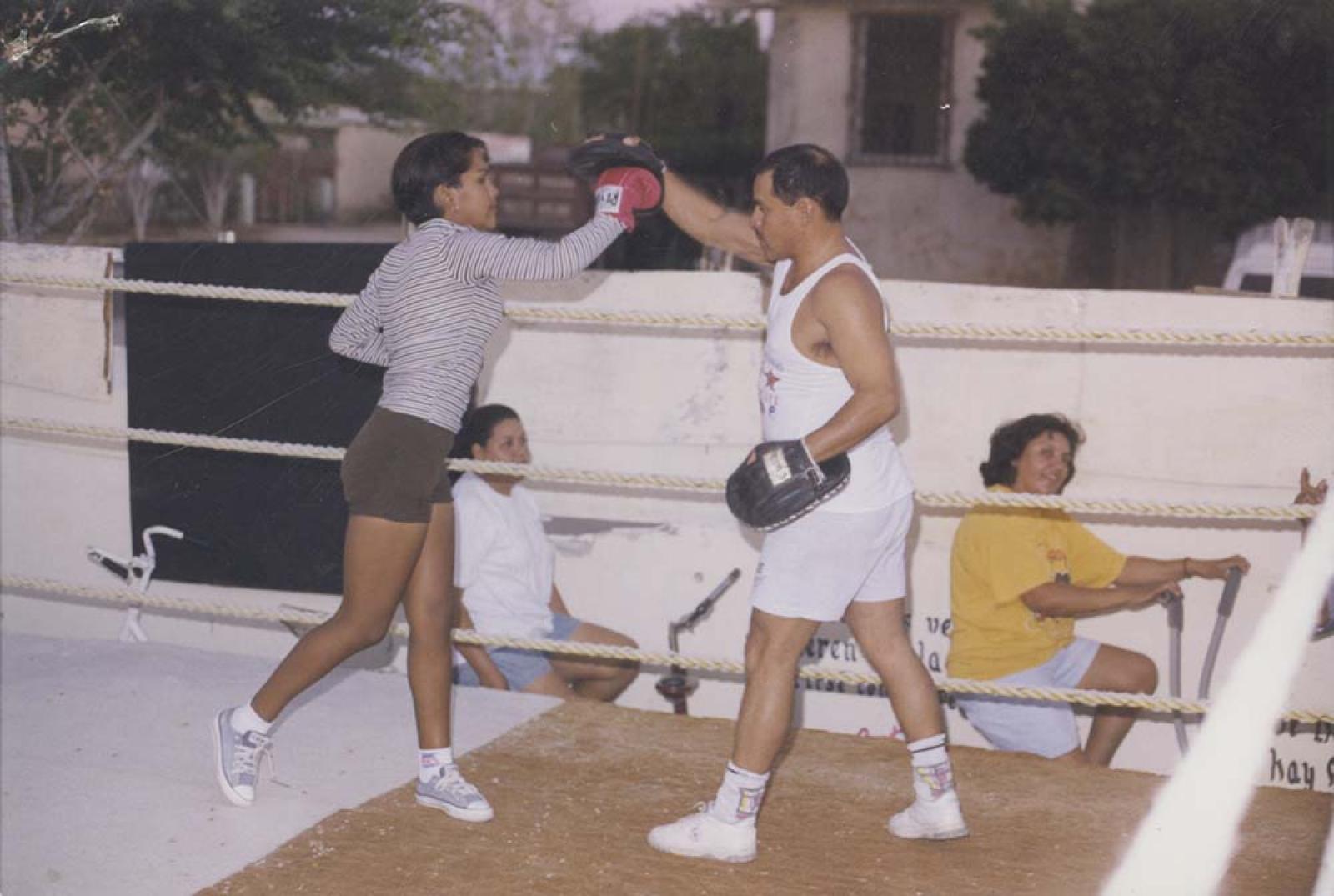 Hombre y mujer boxean, sobre ring.