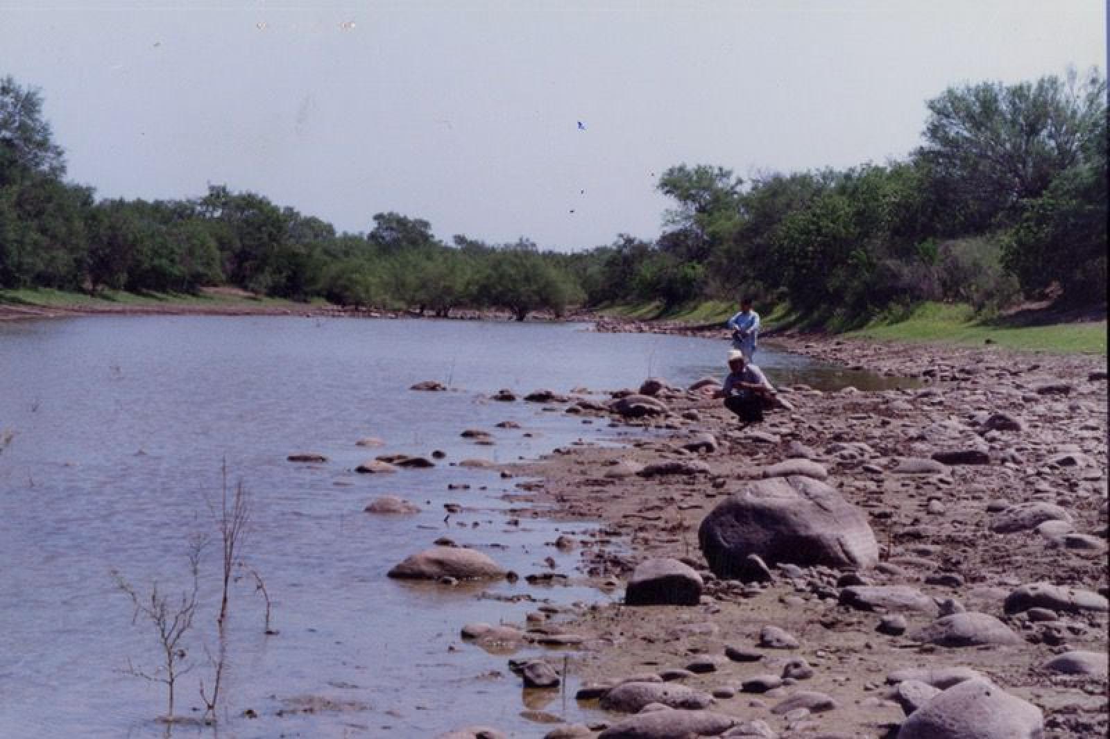Hombres a orillas de arroyo.