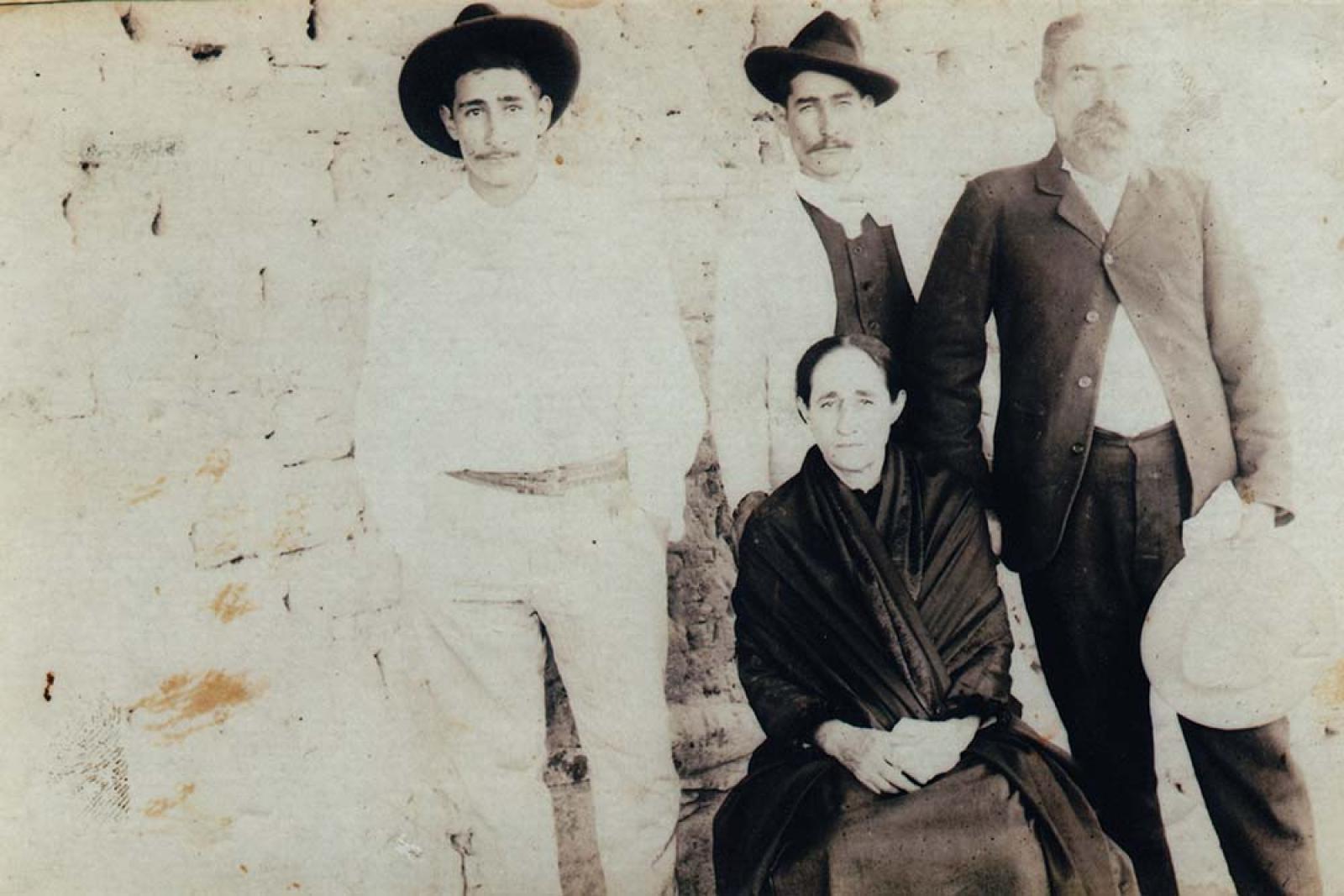 Hombres de pie y mujer sentada.