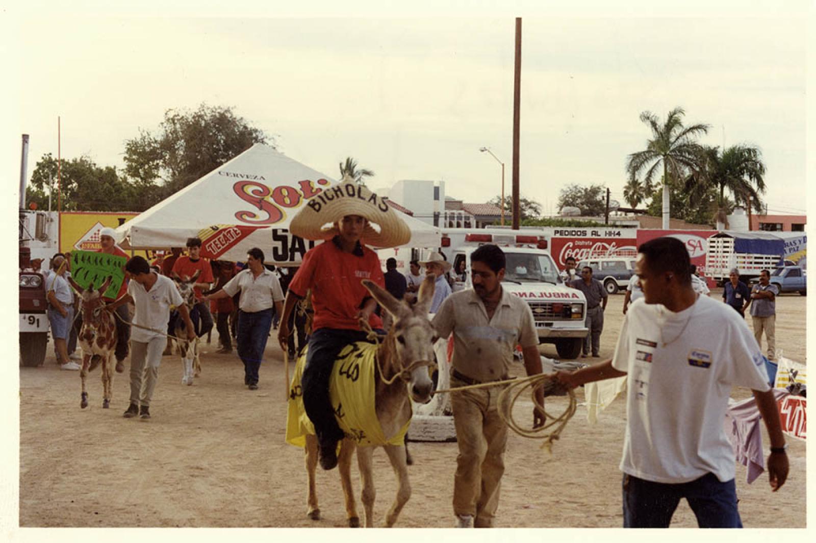 Hombres en carreras de burros en el estadio Arturo C. Nahl.
