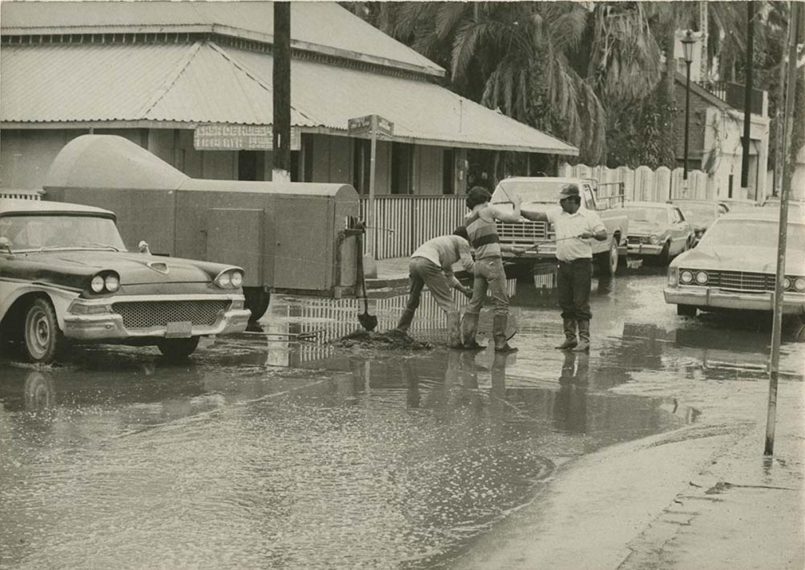 Hombres en trabajos de desazolve, sobre la calle Mutualismo.