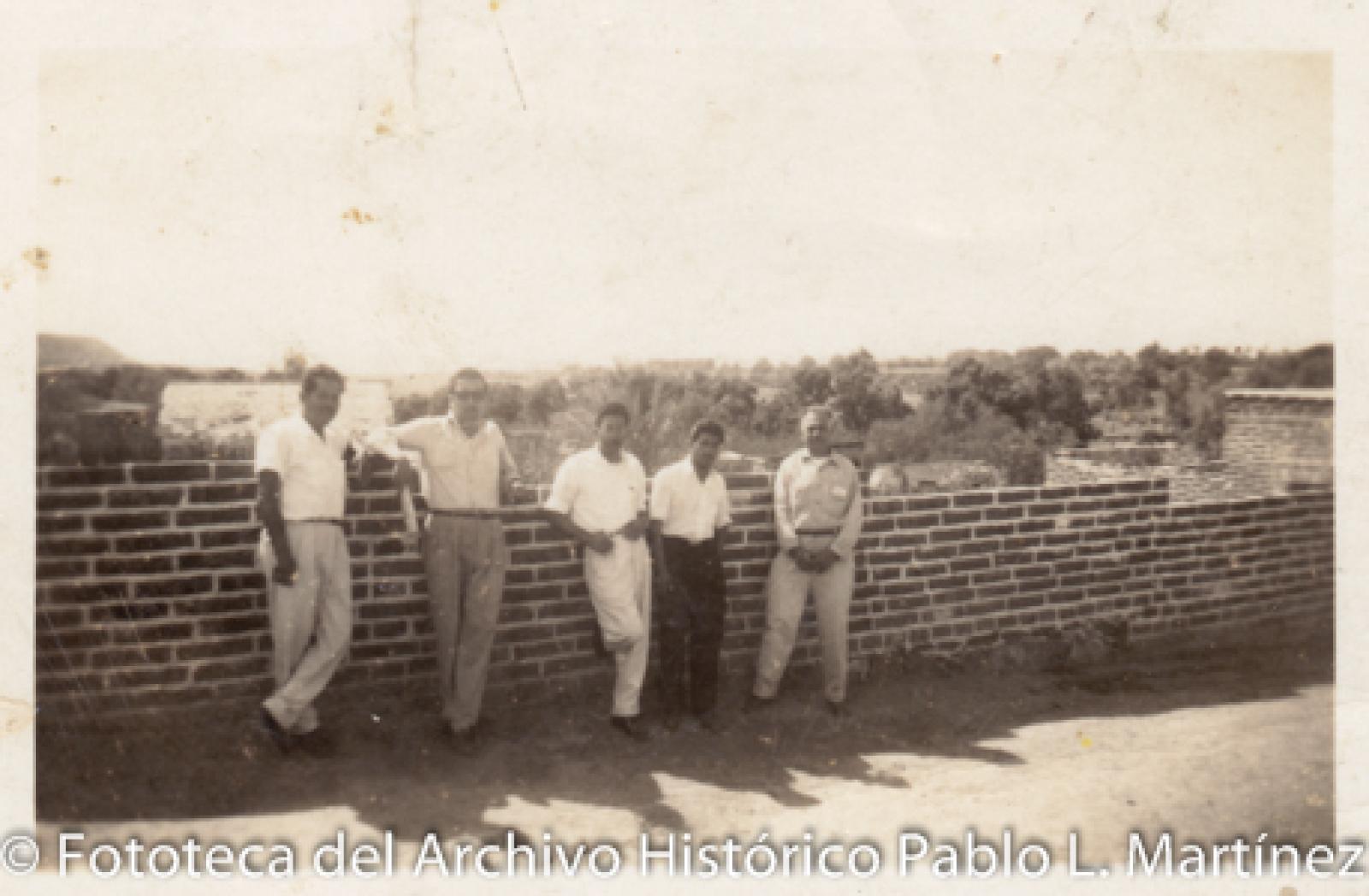 Hombres frente a barda.