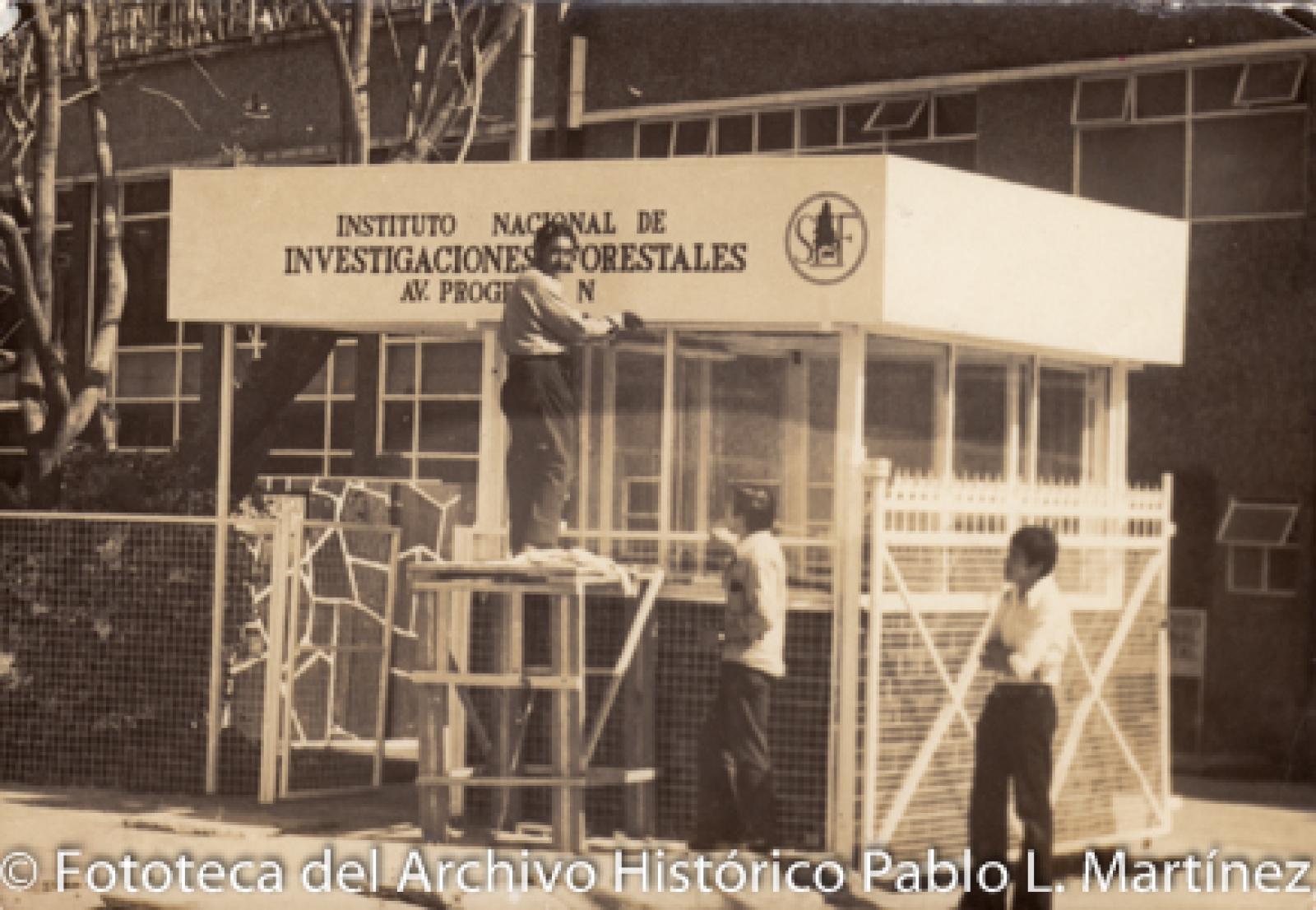 Hombres frente a edificio del “INSTITUTO NACIONAL DE INVESTIGACIONES FORESTALES”.