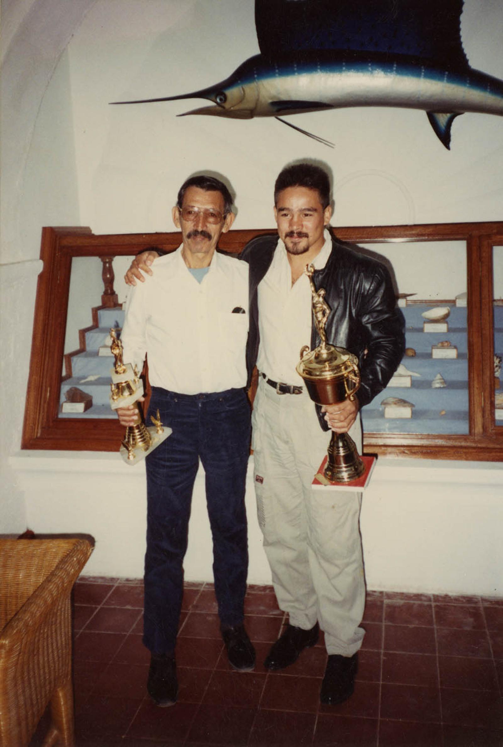 Hombres que sostienen trofeos.