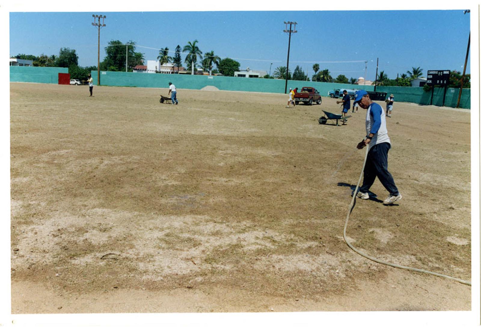 Hombres que trabajan en el mantenimiento del estadio Arturo C. Nahl.