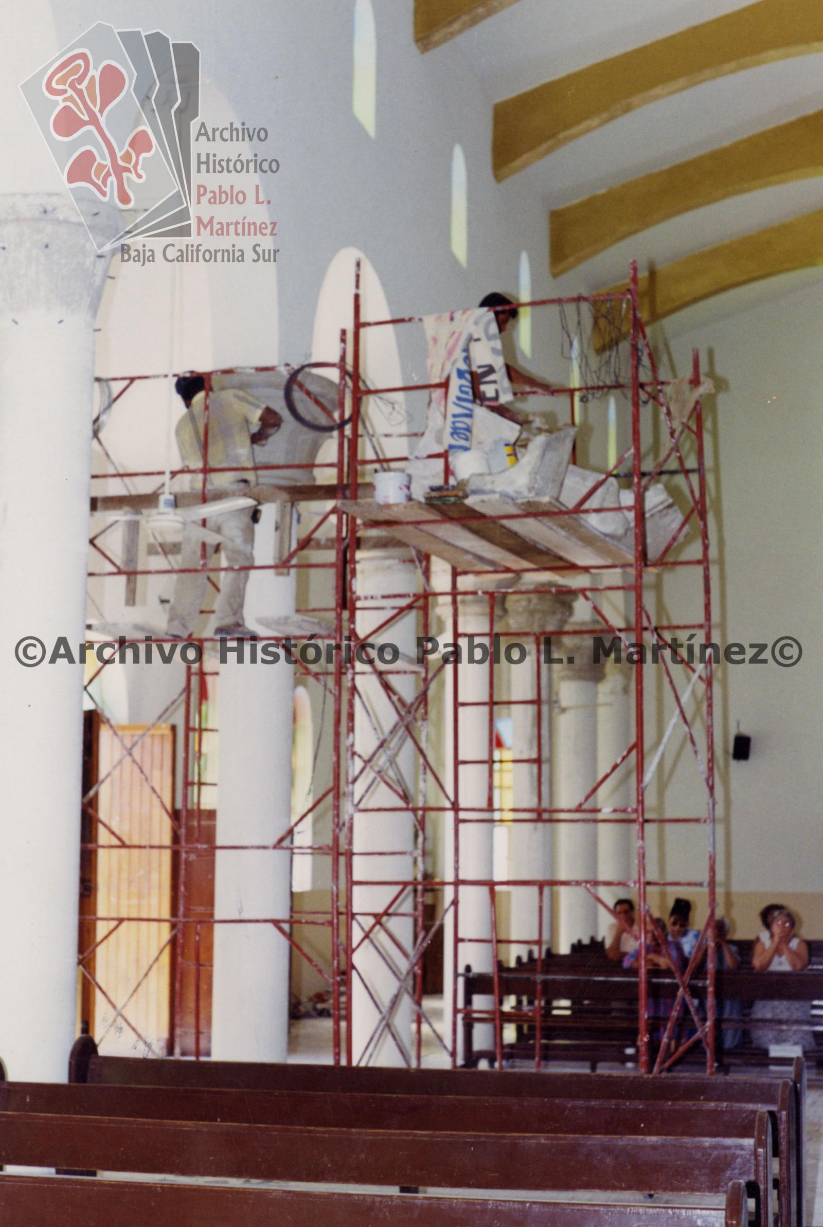 Hombres sobre andamio, dan mantenimiento a interior de templo de Nuestra Señora de Lourdes en Constitución, Baja California Sur.