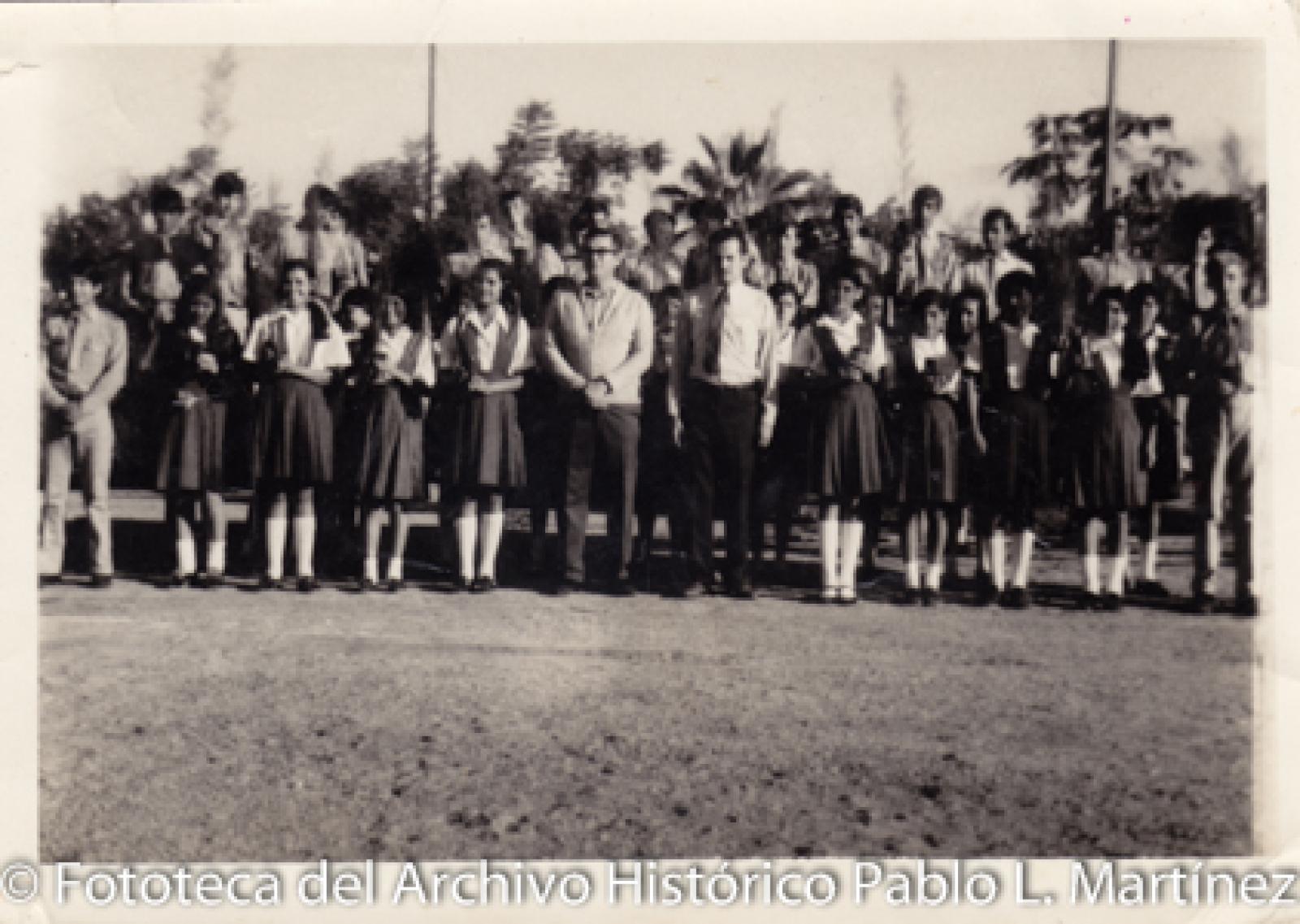 Hombres y jóvenes con uniforme escolar al aire libre.