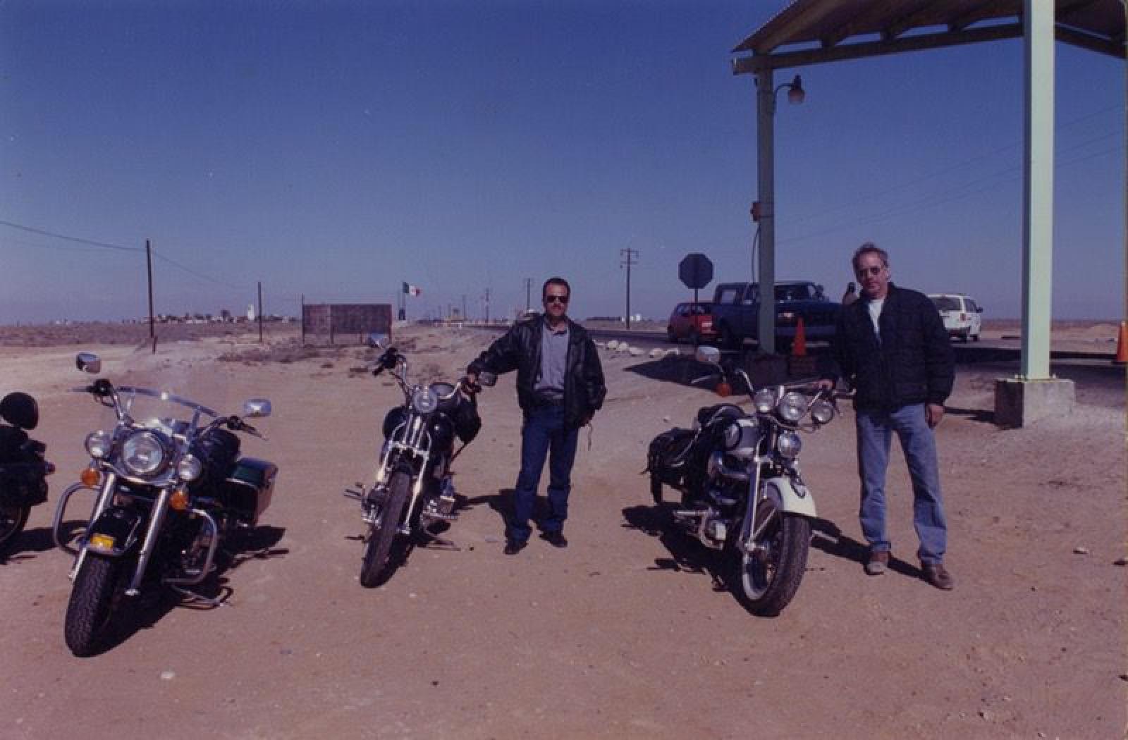Hombres y motocicletas, a costado de tramo carretero.
