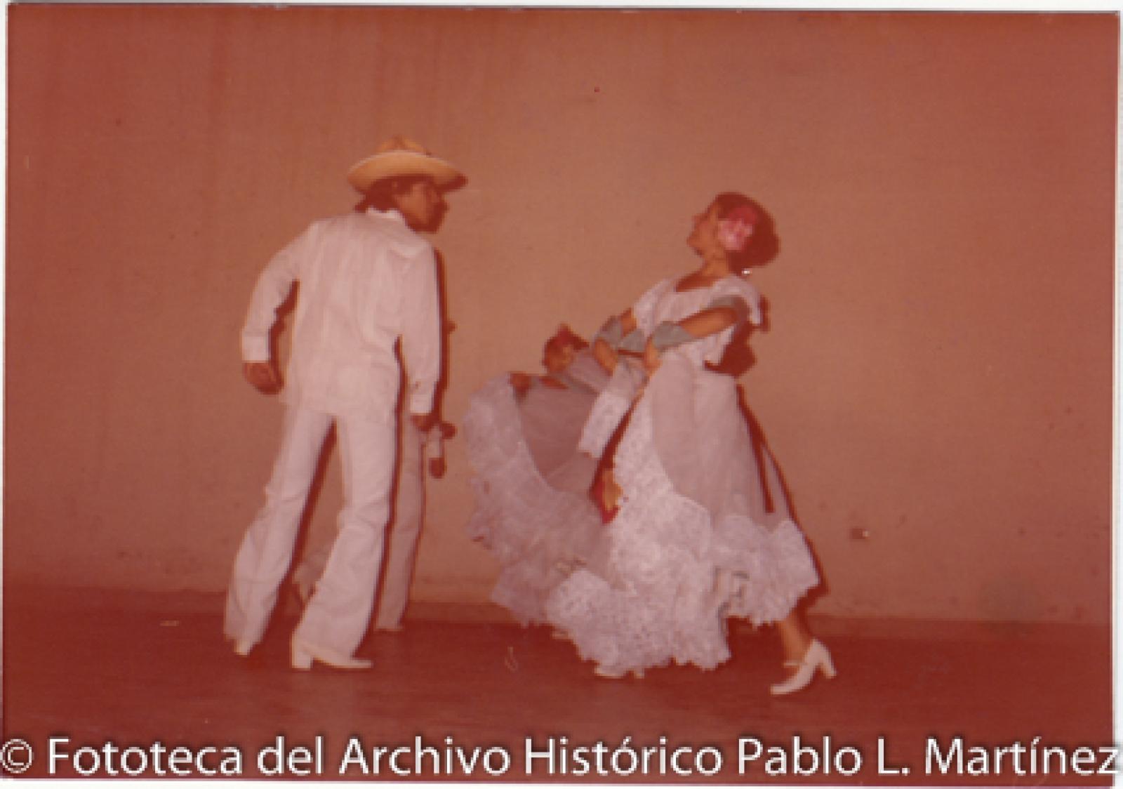 Hombres y mujer bailan danza folklórica.