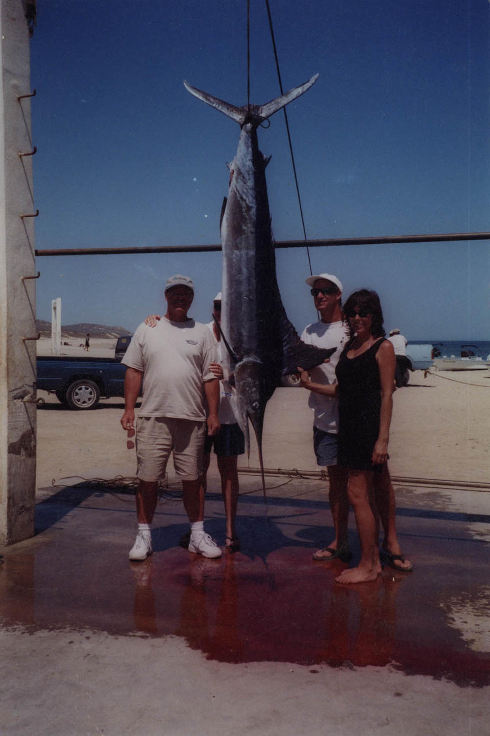 Hombres y mujer junto a pescado Marlín, retrato.