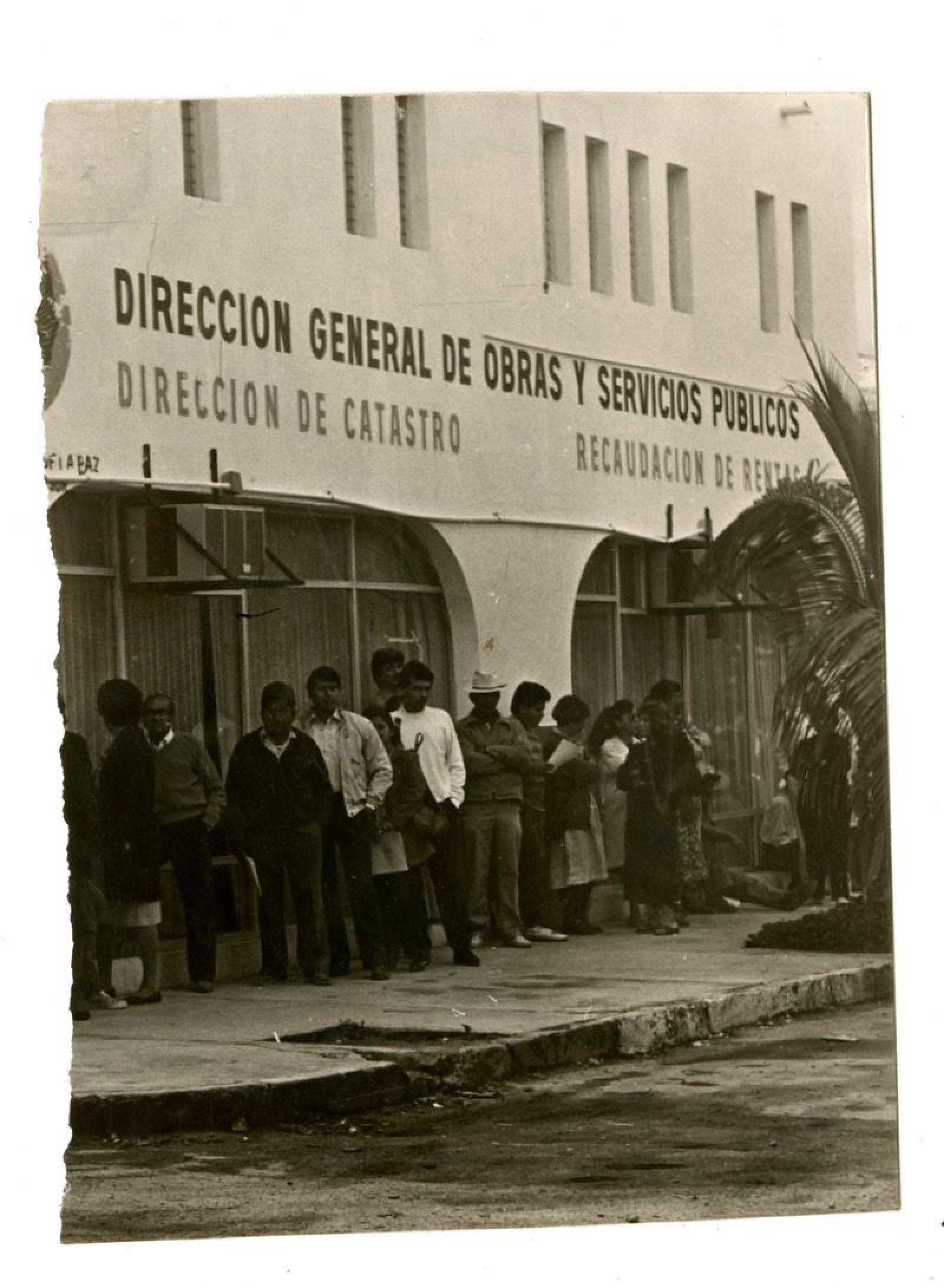 Hombres y mujeres afuera de las instalaciones de la Dirección General de Obras y Servicios Públicos.