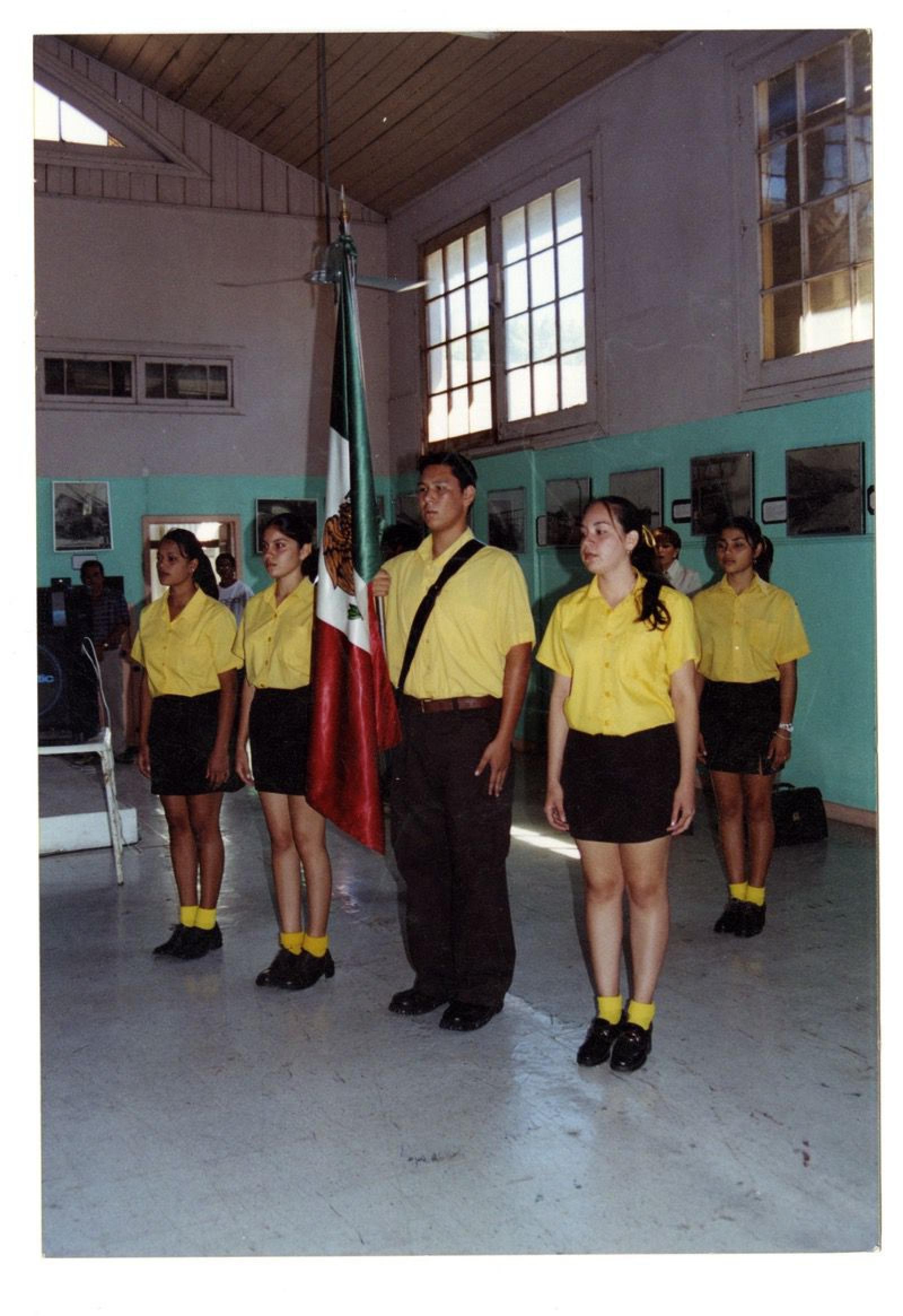 Hombres y mujeres en honores a la bandera mexicana.