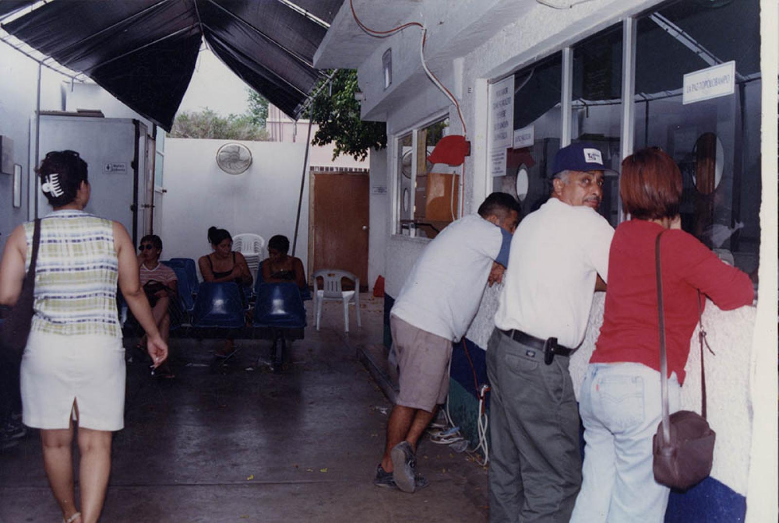 Hombres y mujeres en taquilla de boletos para viajar en barco.