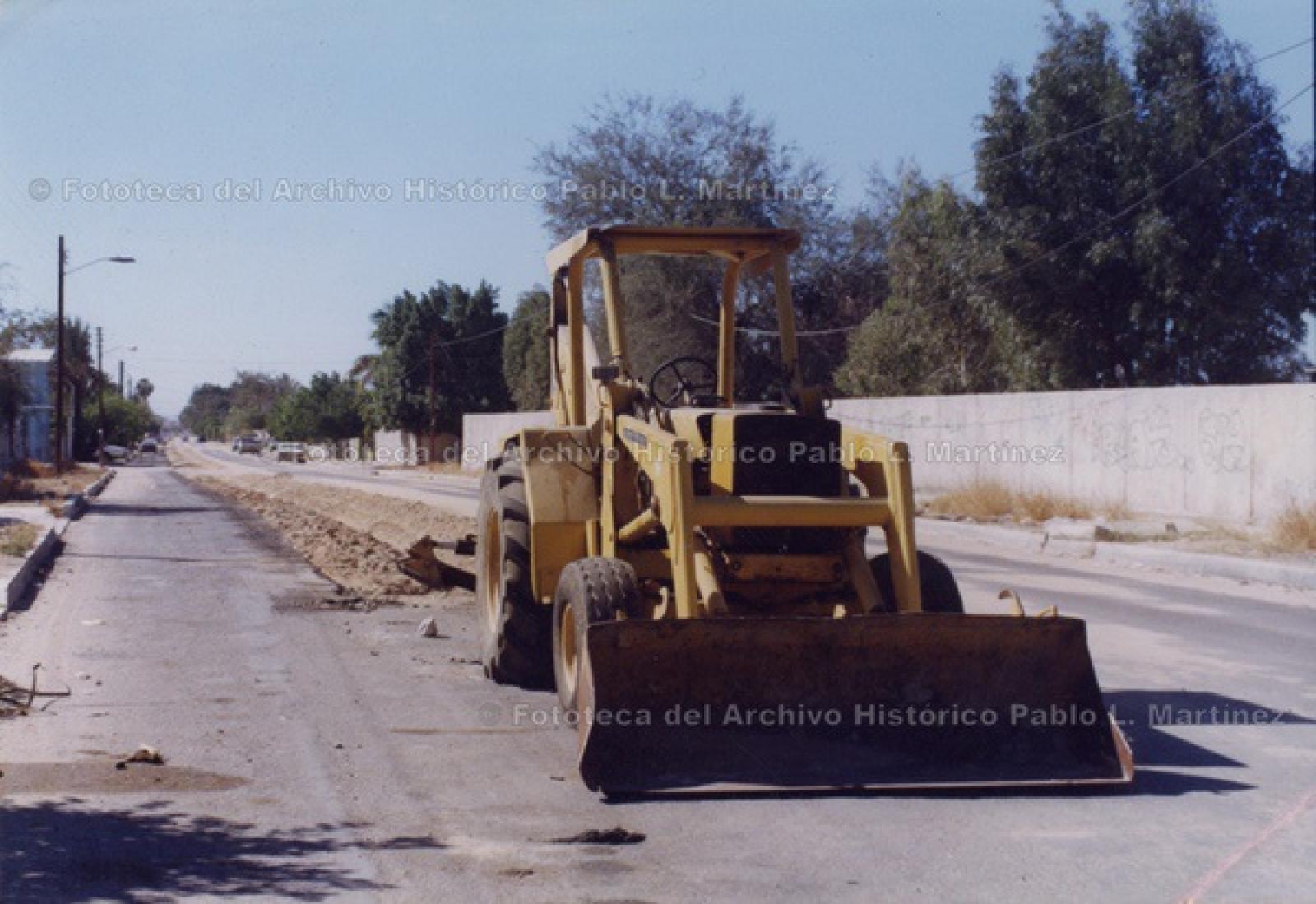 Máquina excavadora sobre calle en obra pública.