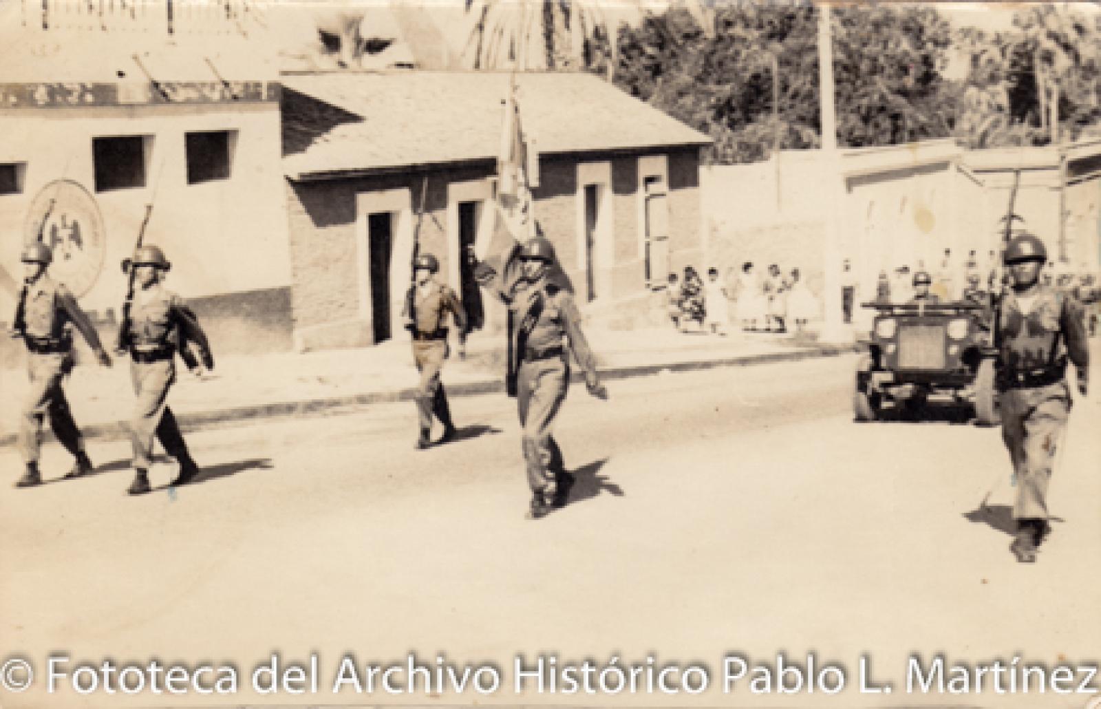 Militares que desfilan frente a civiles y casas