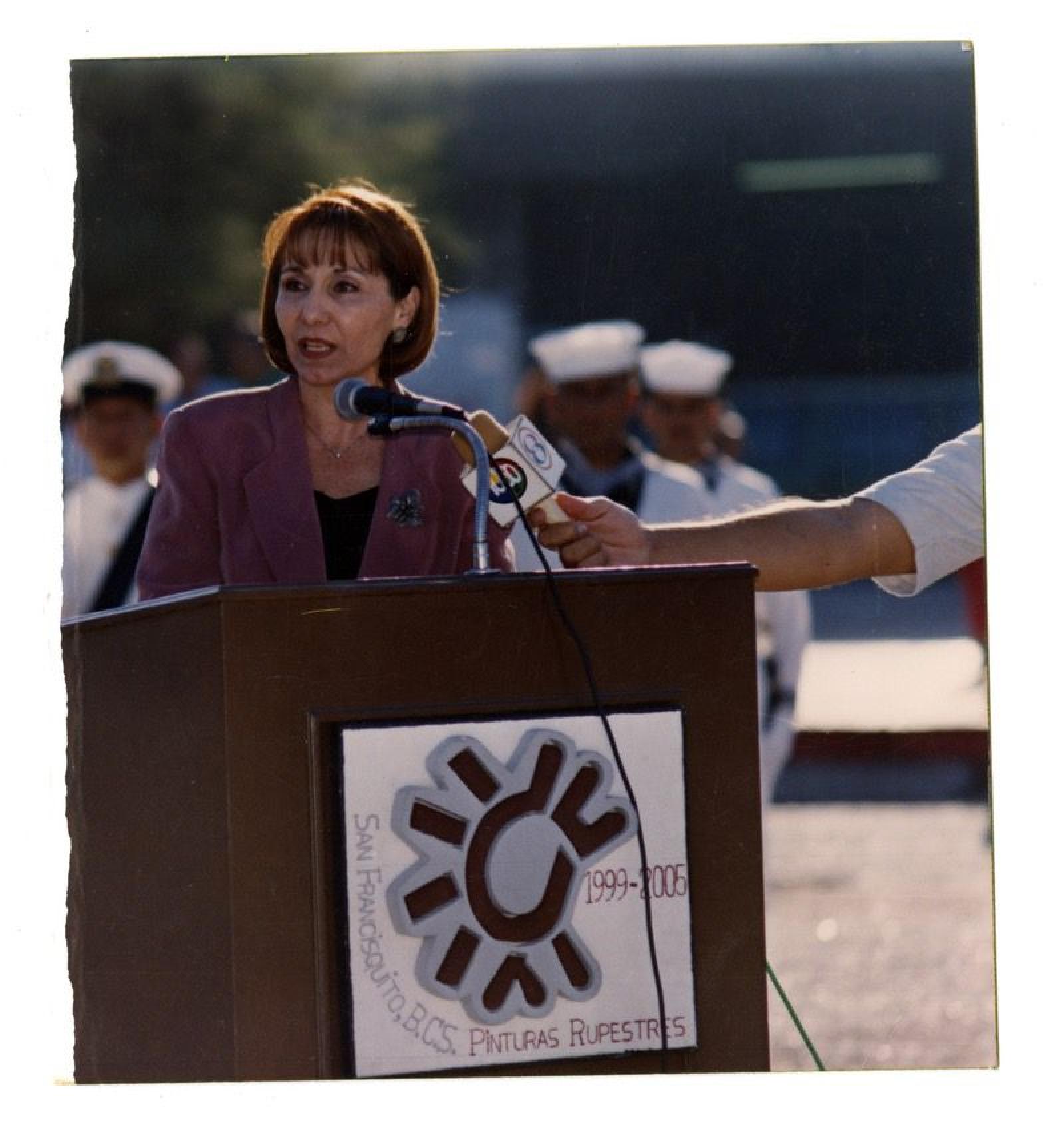 Mujer dando discurso en evento.